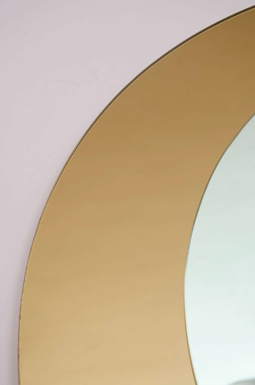 Cristal Arte mirror composed of two circular discs, one of bronze mirror, the other silver, positioned asymmetrically by two large brass rivets.