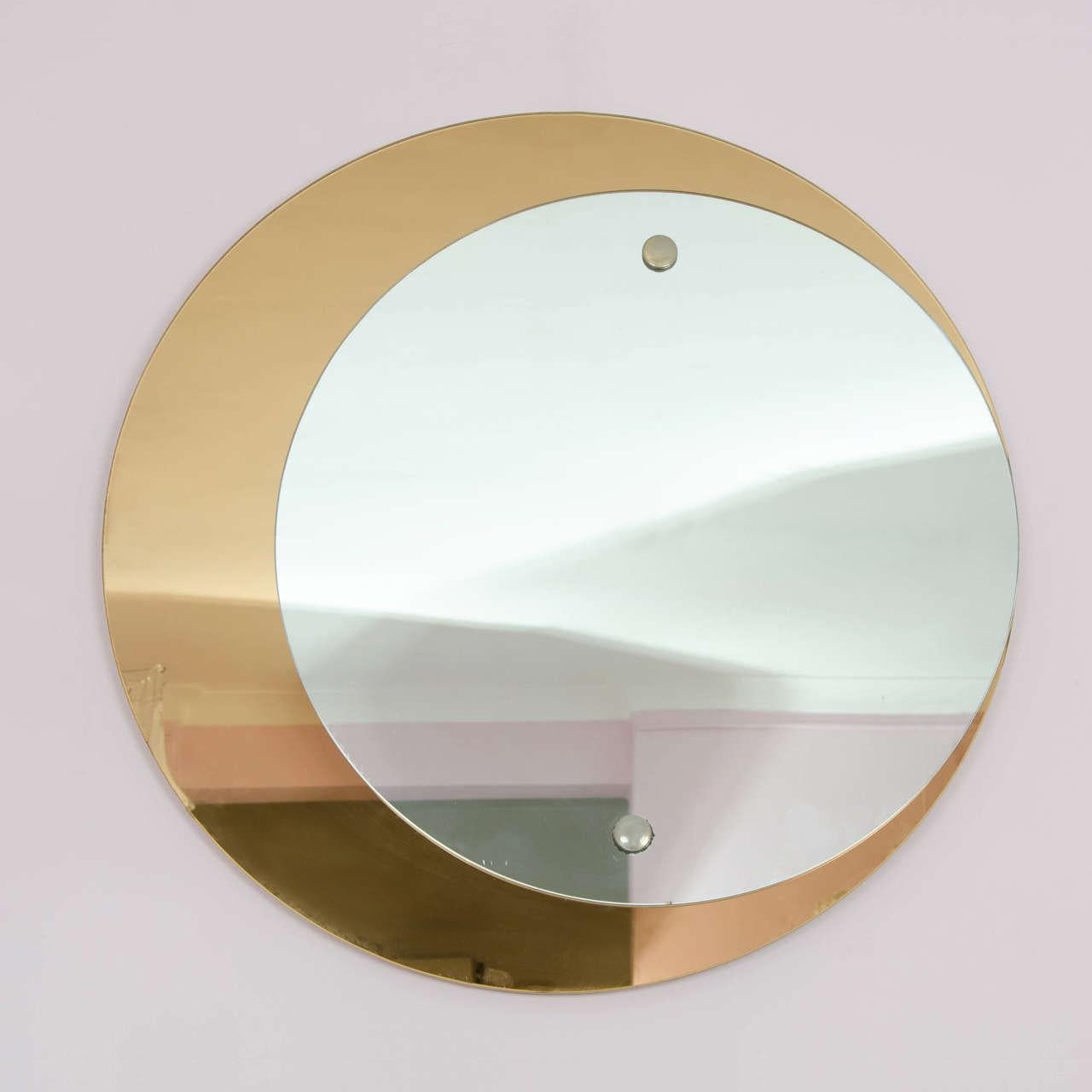 Specchio di Cristal Arte composto da due dischi circolari, uno in bronzo e l'altro in argento, posizionati in modo asimmetrico da due grandi rivetti in ottone.