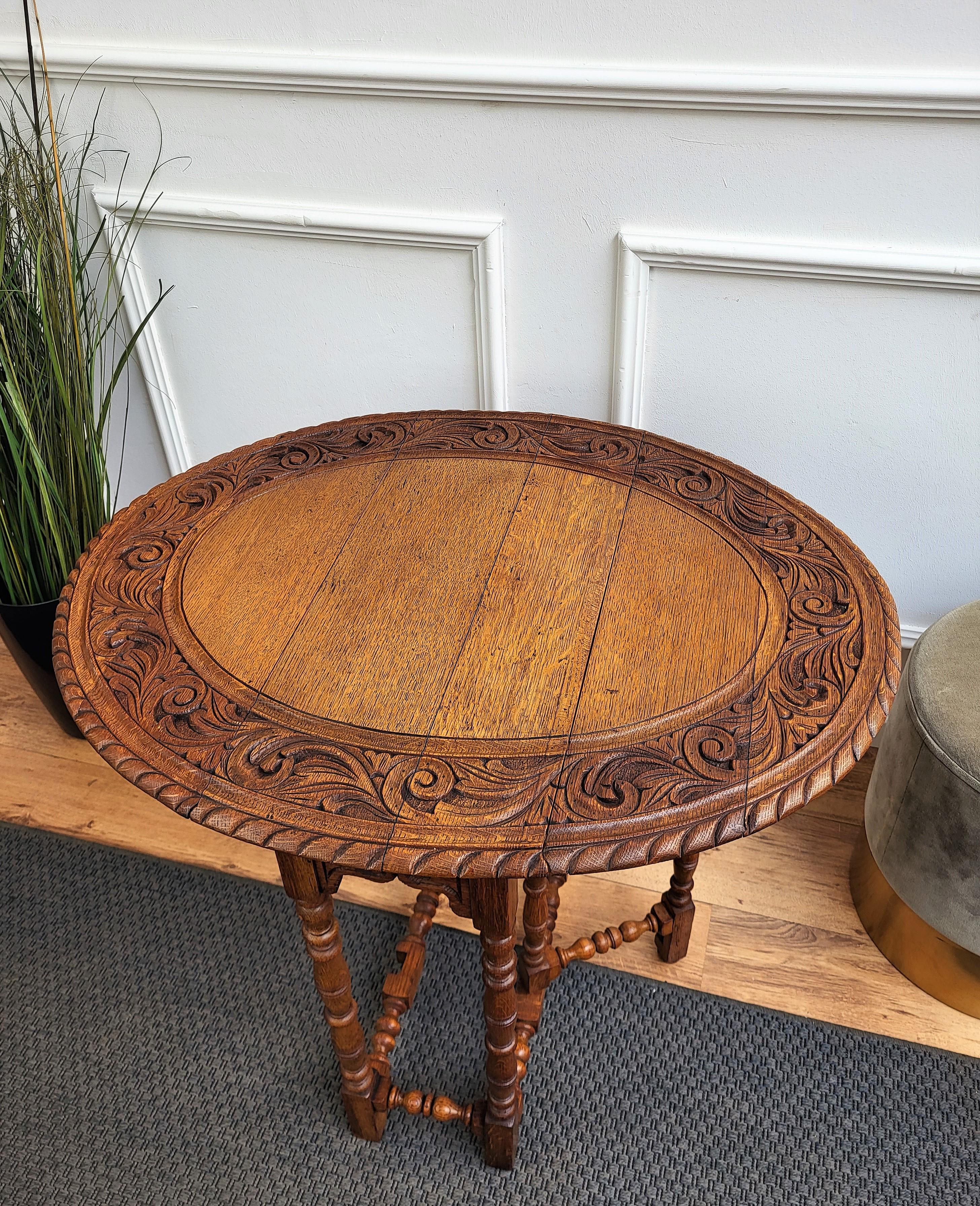 A small Italian drop leaf top with curved corners upon bobbin barley turned legs on all four sides and the gates. The table also features an oval table top with carved decorations and beveled edges, pear shaped feet, and a lower box stretcher for