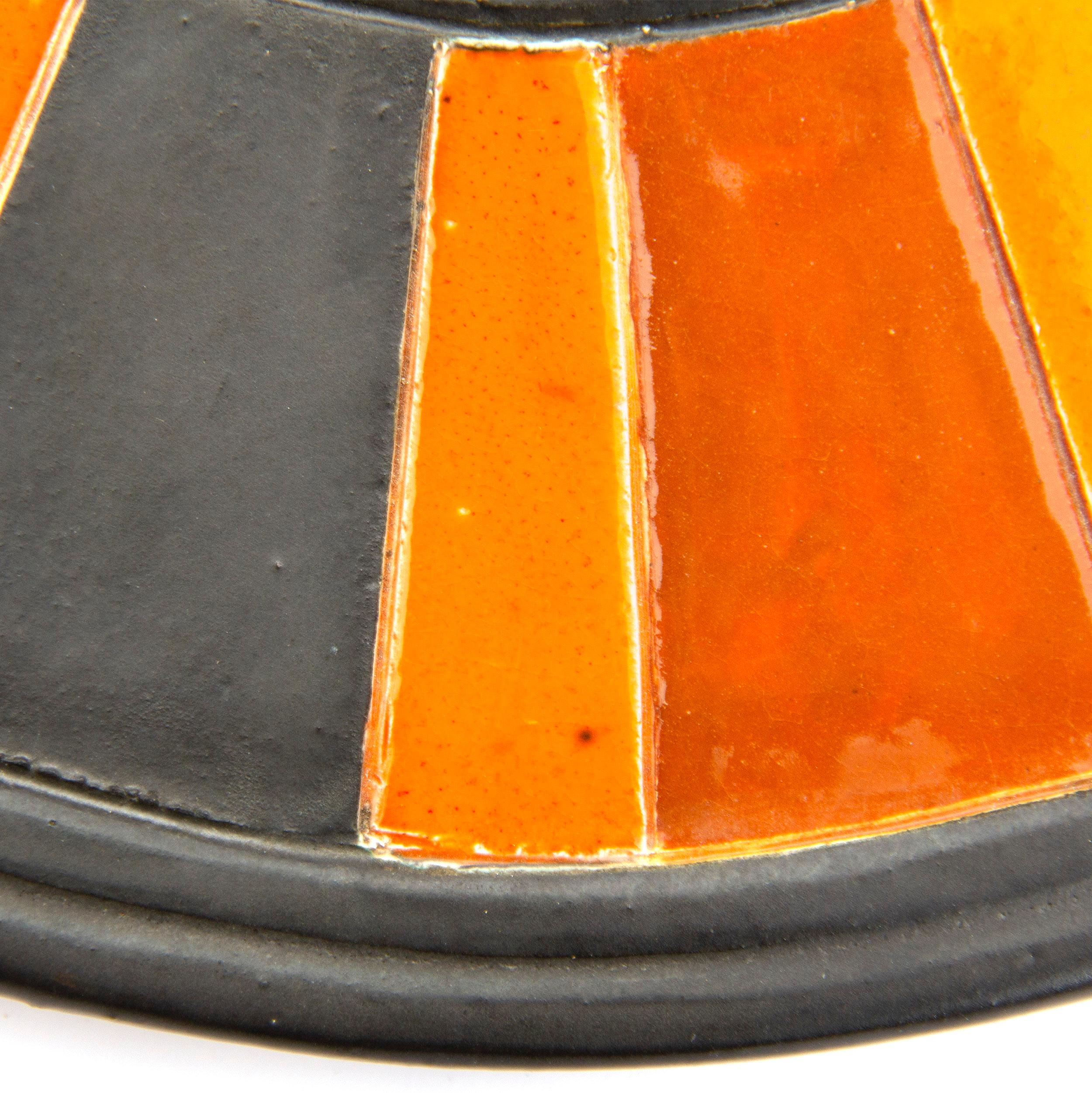 Round ceramic mirror with 'sunburst stripes' of orange, red and brown.