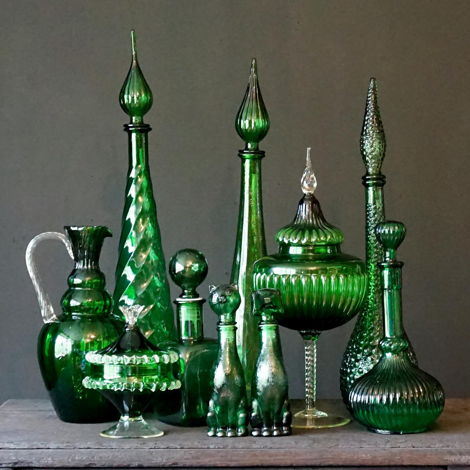 Spectacular set of ten 1960s green Italian Empoli pressed and blown glass. Three genie bottles, a mini dog shaped bottle and a cute cat shaped one. A large handblown two color pitcher, a 'corset' decanter. A Brutalist 'block' shaped decanter with a