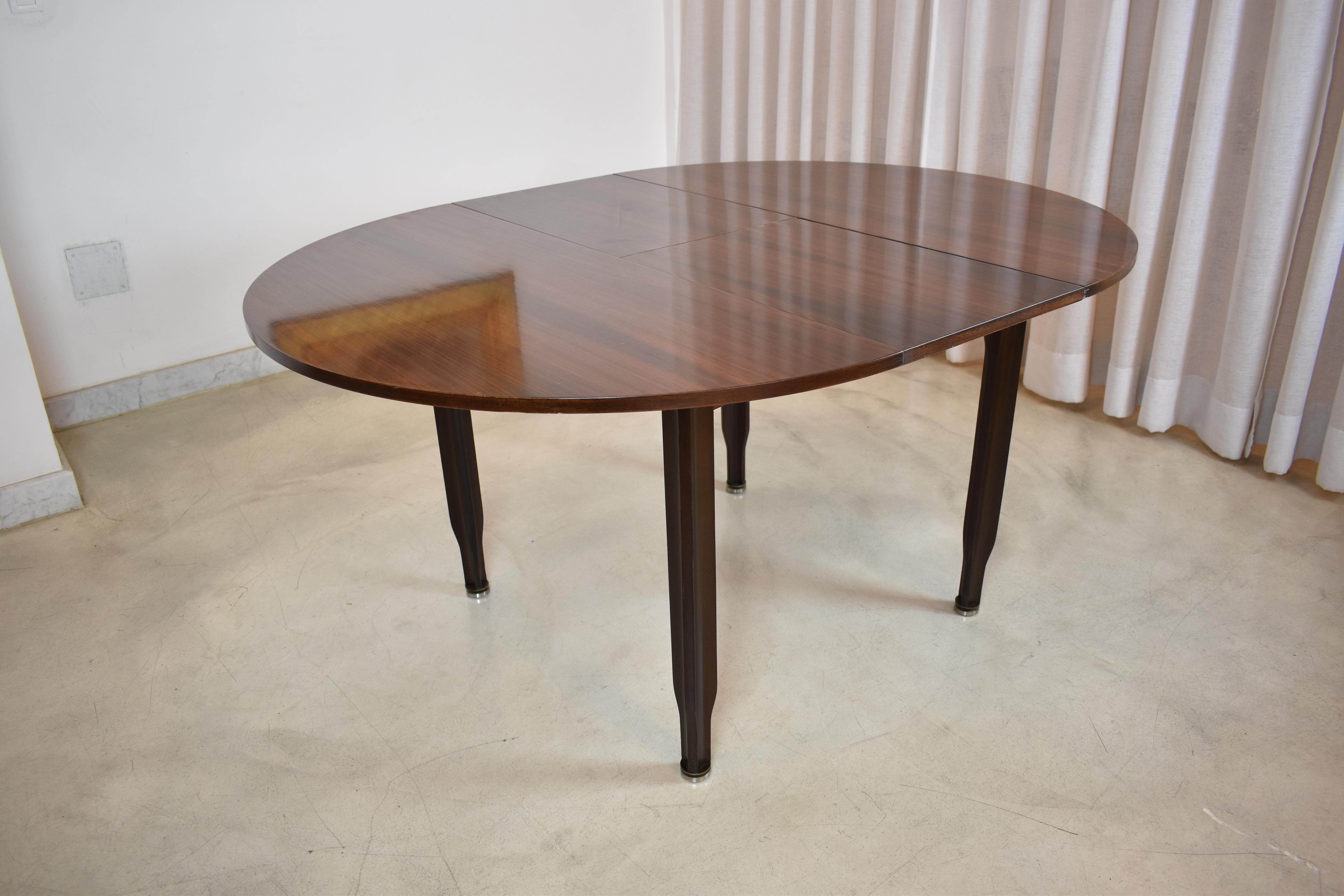 A stunning Italian vintage round extendable dining table composed of solid noble hardwood with a deep, rich color and striking grain patterns. and highlighted by stylish metallic caps. 
This beautiful collectible piece had undergone impeccable