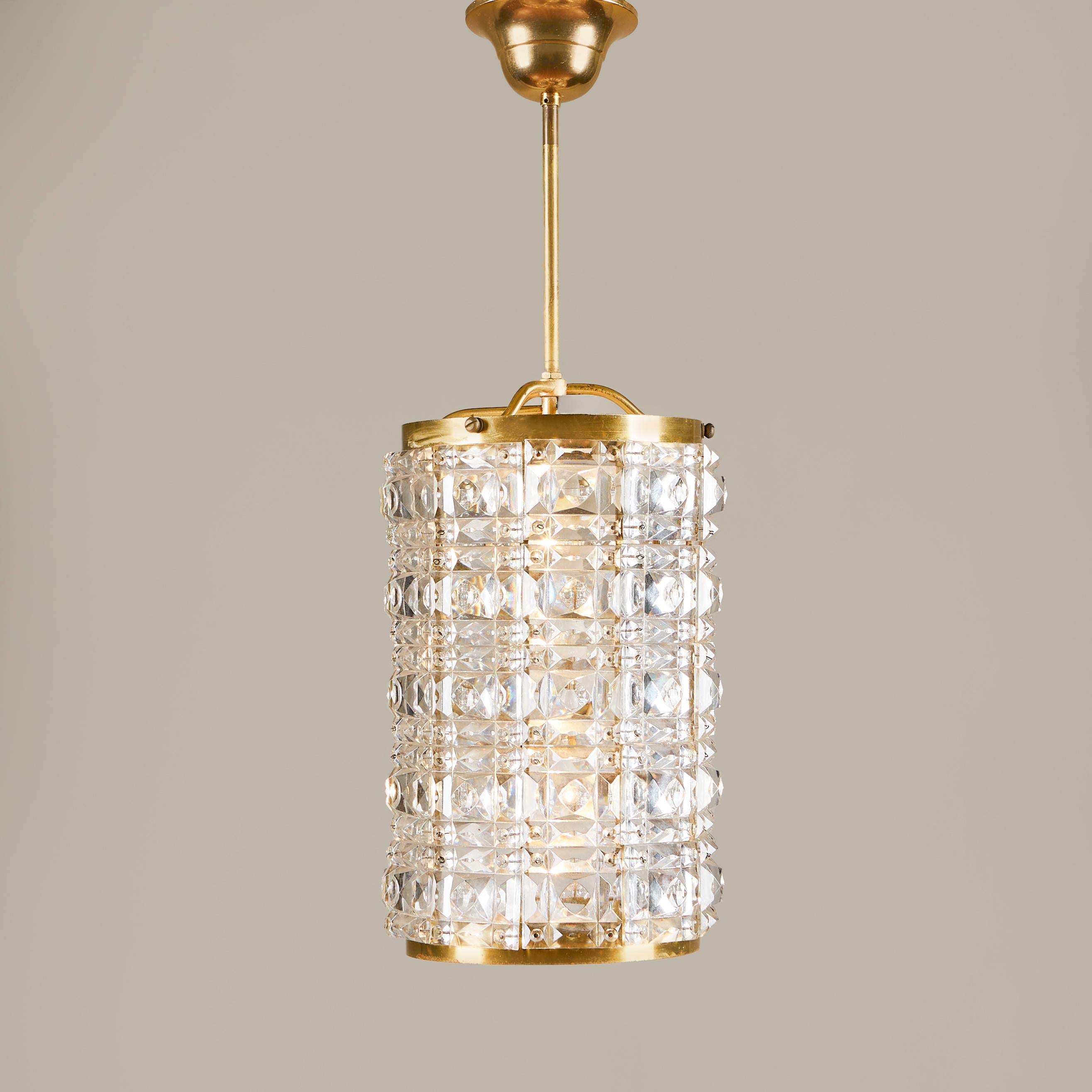 Impressive brass cylindrical pendant made up of multiple squares of faceted glass to create a jewel effect that exudes a lovely diffused light. The pendant is finished with a brass trim to the top and bottom and original brass rod and ceiling