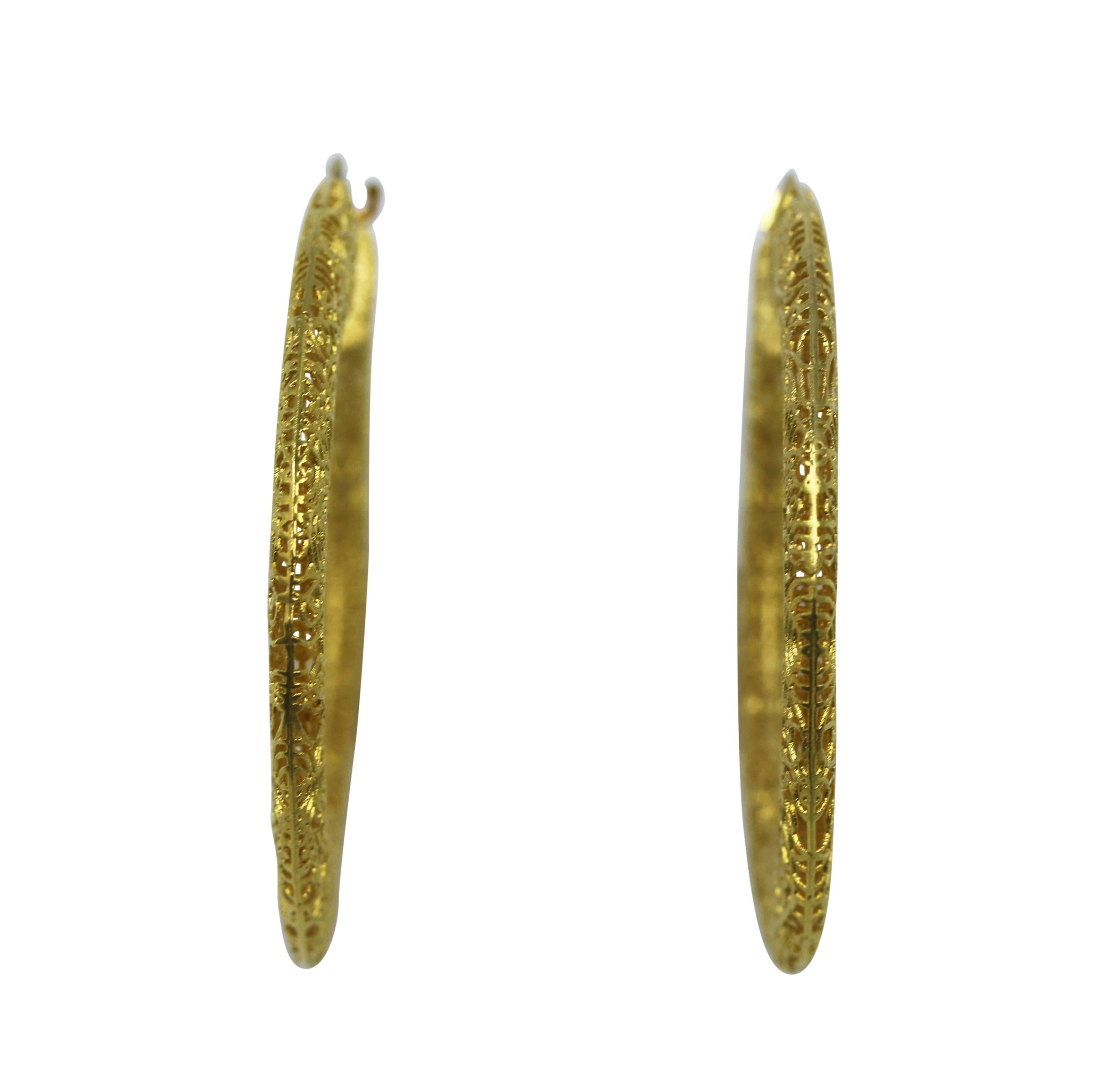 Pair of 14 karat yellow gold filigree earrings, Italian, circa 1960, designed as openwork hoops of circular and web patterns, gross weight 10.2 grams, measuring 1 7/8 by 2 by 1/8 inches.
A fun alternative to traditional hoop earrings with a unique