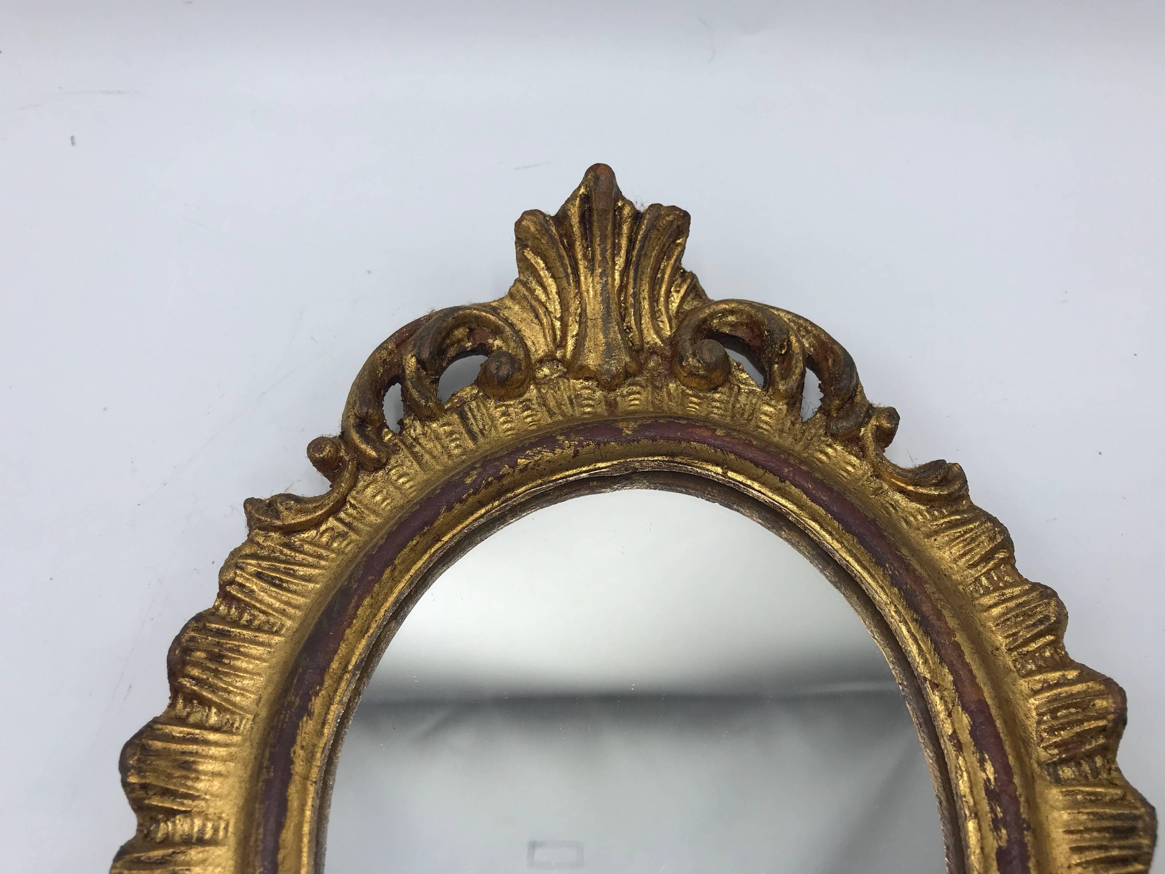 Listed is a gorgeous, small/medium, 1960s Italian Florentine oval gilded mirror. Beautiful, carved ornate detailing.