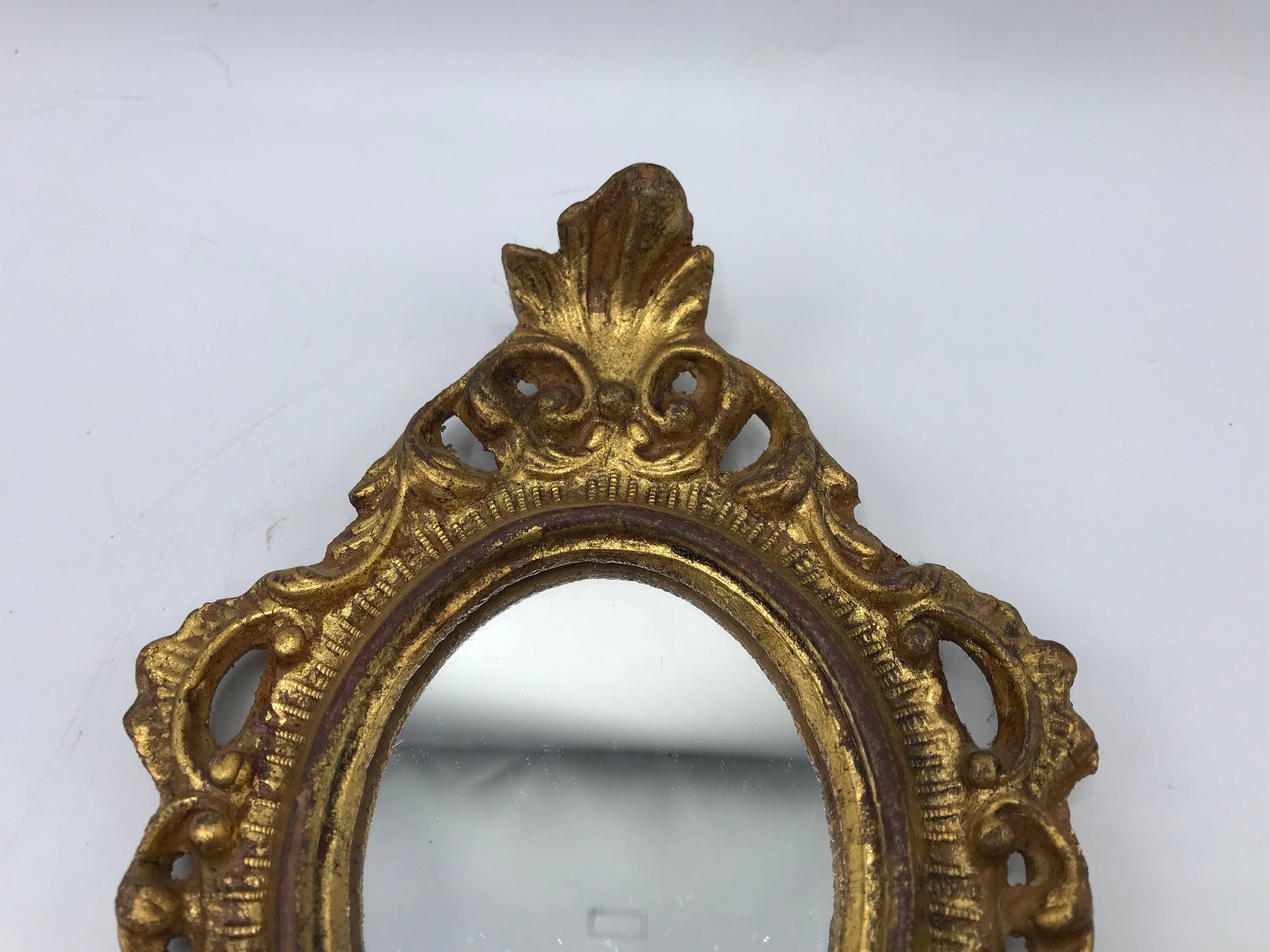 Listed is a gorgeous, small, 1960s Italian Florentine oval gilded mirror. Beautiful, carved ornate detailing. Marked on backside.