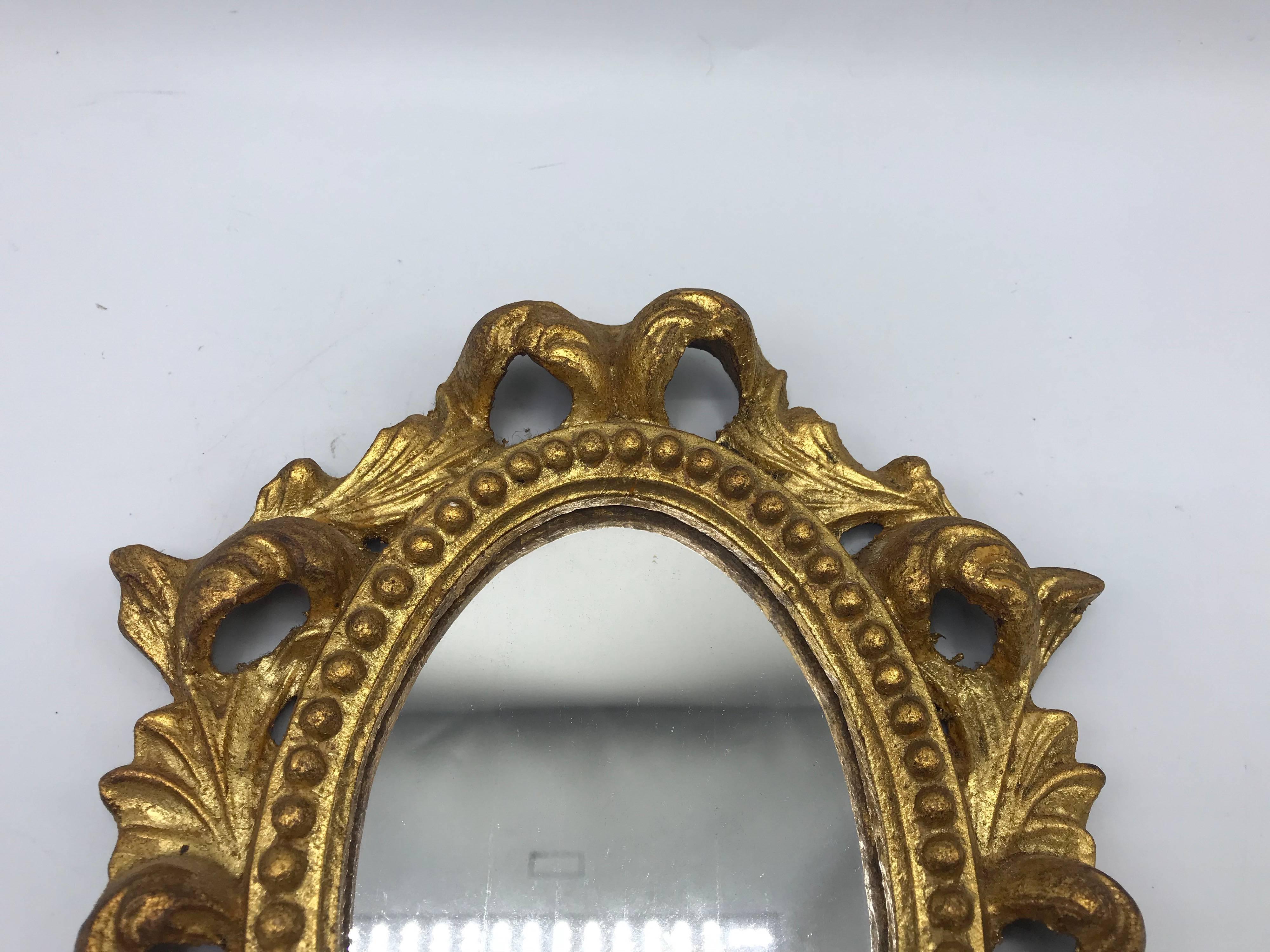 Listed is a gorgeous, small or medium, 1960s Italian Florentine oval gilded mirror. Beautiful, carved ornate detailing.