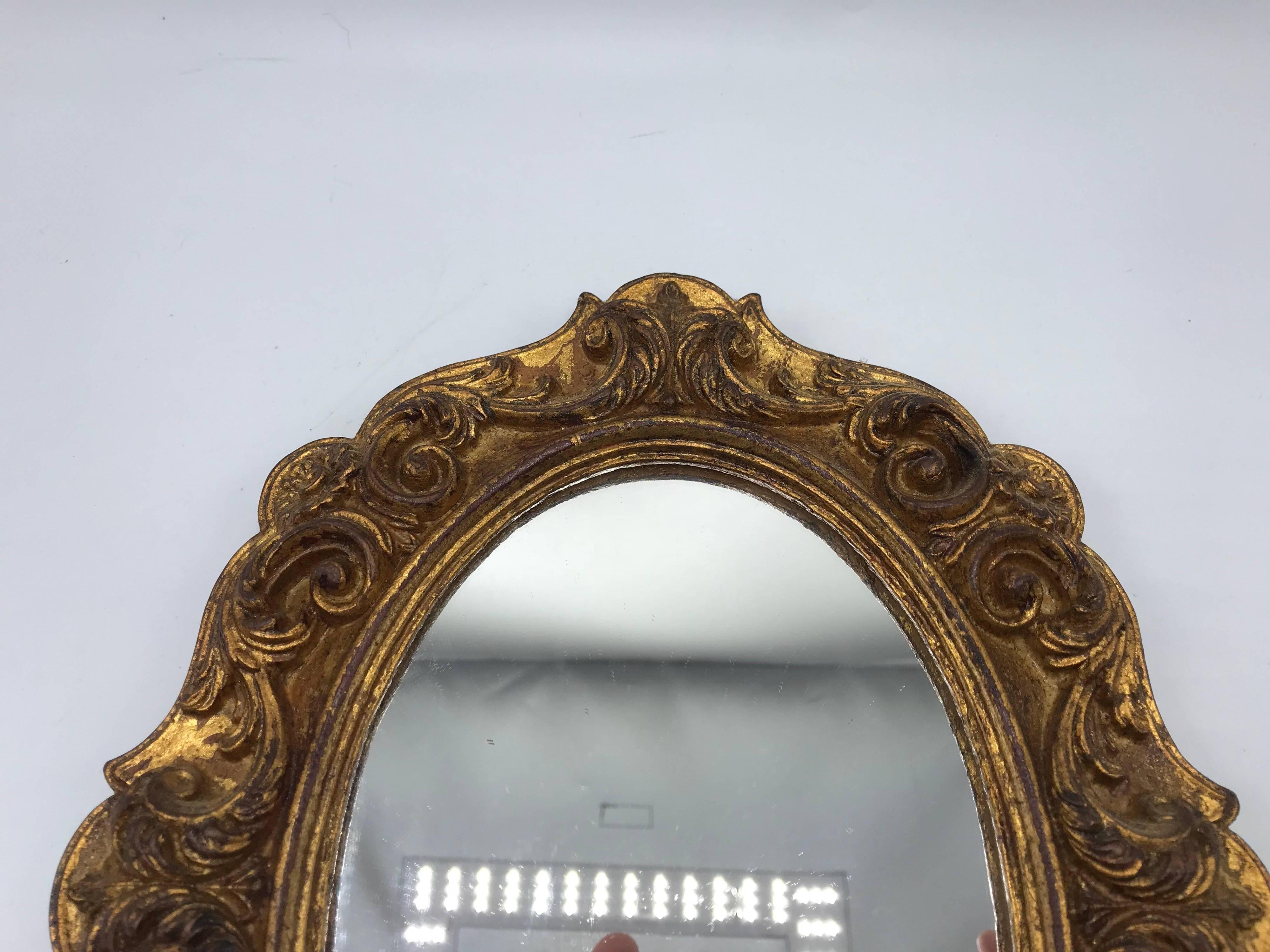 Listed is a gorgeous, small or medium, 1960s, Italian Florentine oval gilded mirror. Beautiful, carved ornate detailing.