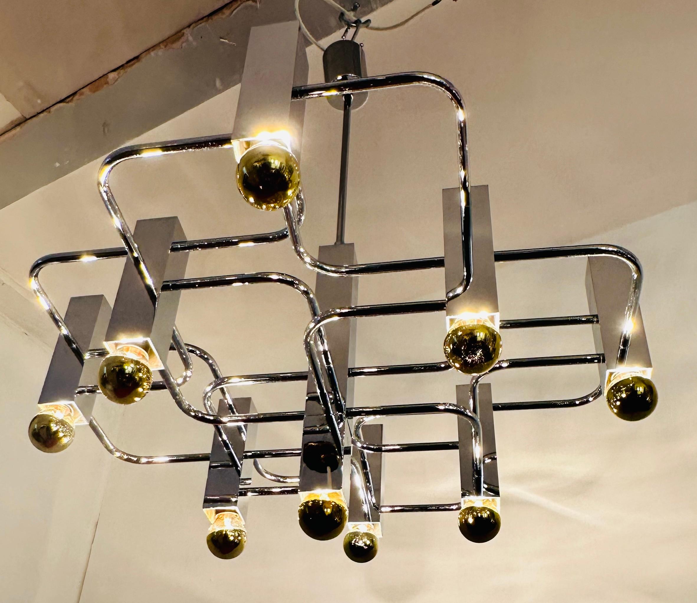 A stunning and striking polished chromed-metal geometric chandelier designed by Gaetano Sciolari for S.A. Boulanger in Italy during the 1960s.  The 9 vertical chromed square bulb holders are connected by interconnecting horizontal thin chromed-metal
