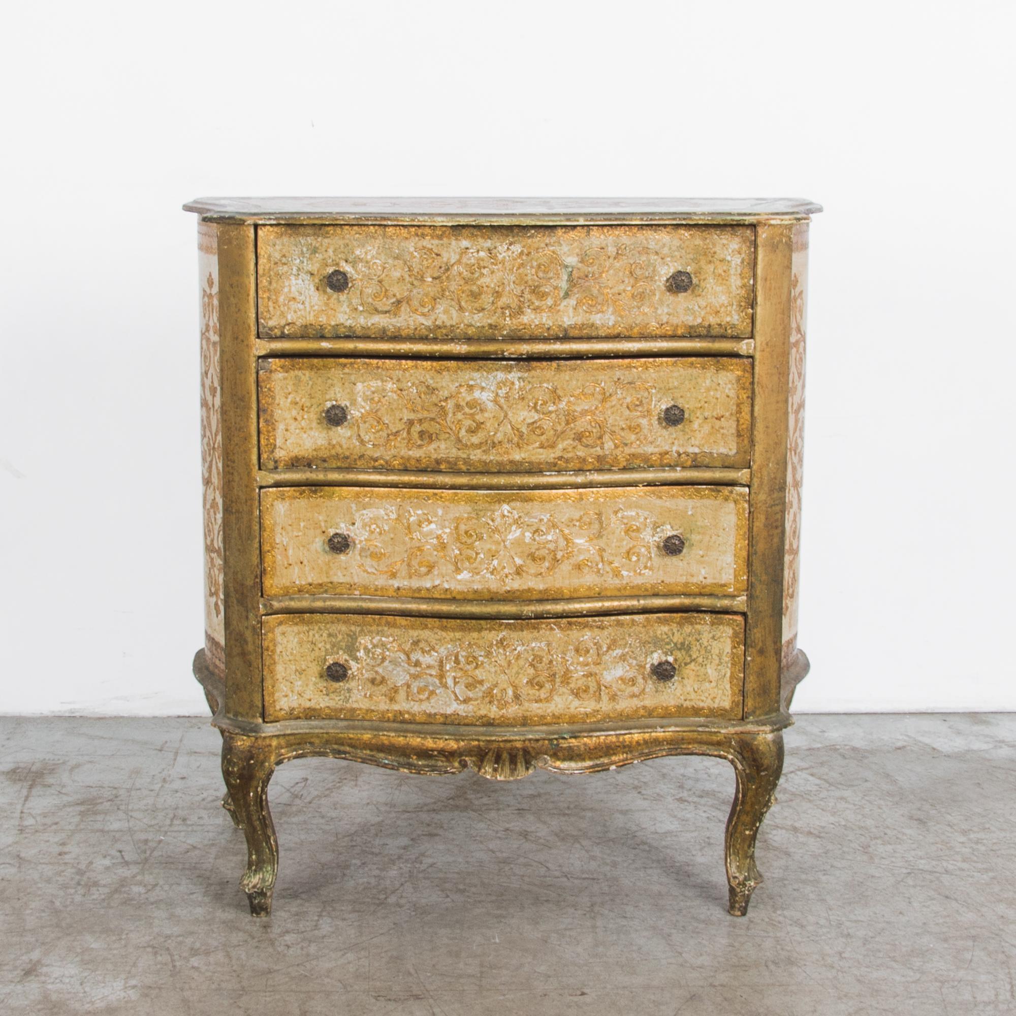 A gilded wooden chest of drawers from Italy, circa 1960. Elegantly aged, a refined shape is contrasted with a textured patina and elaborate carved ornament.

The four pull-out drawers have a gentle serpentine curve, echoed by curving side panels,