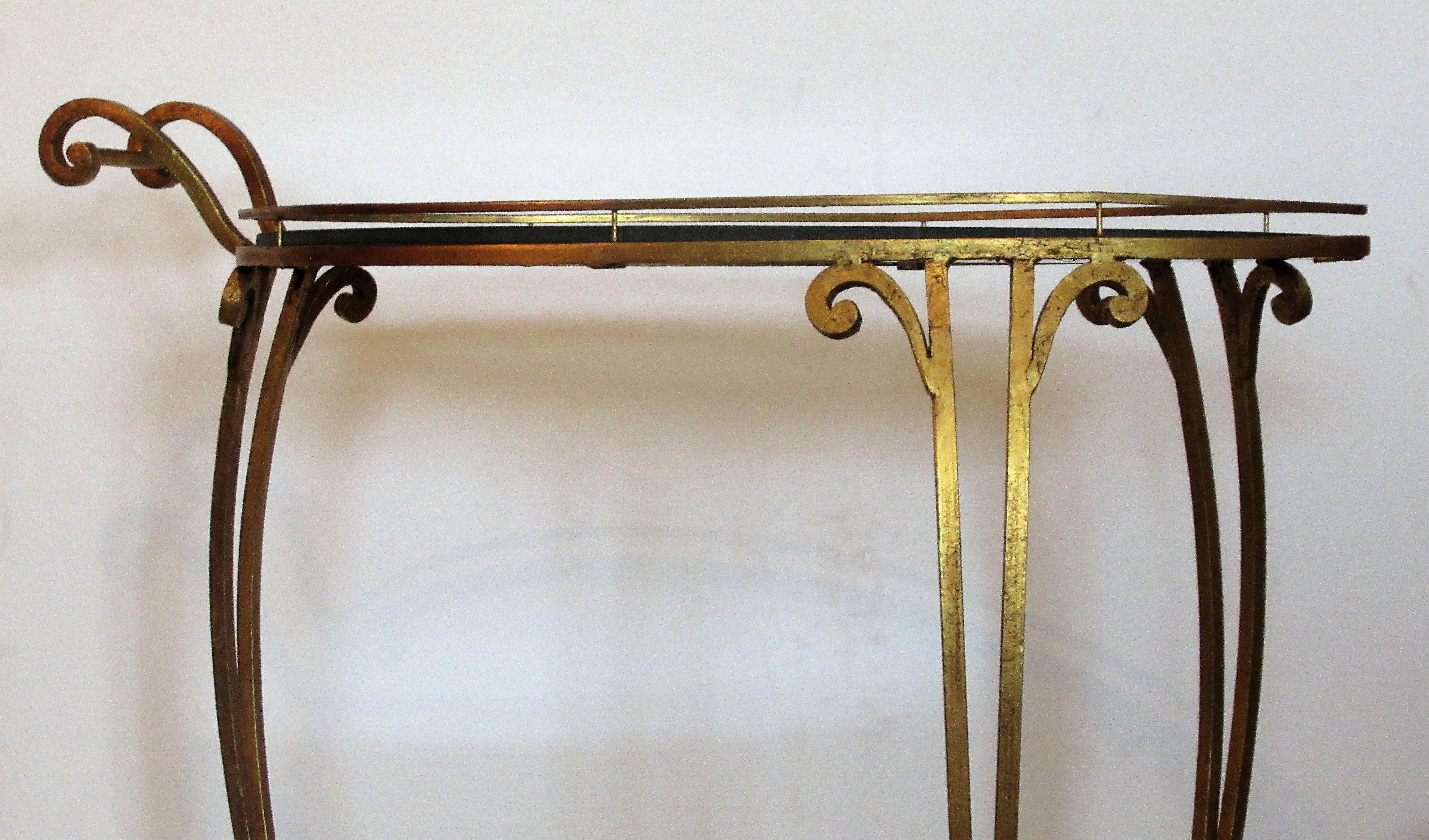 1960s Italian gilt iron rolling bar serving cart with three casters and removable upper and lower oval plate glass shelves (12 inches high to top of lower glass shelf / 30 inches high to top of upper glass shelf) The original gilding in beautifully