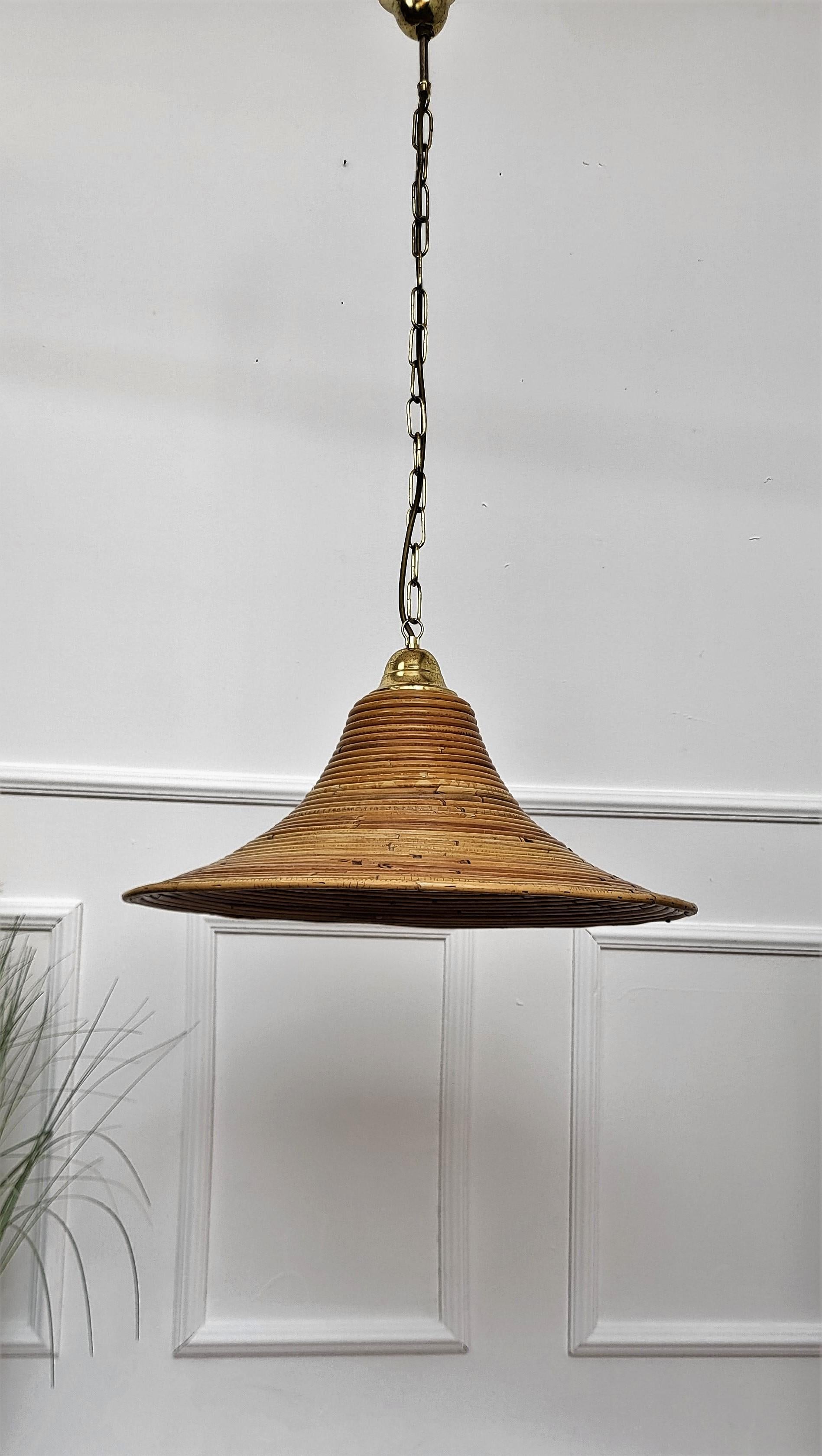 Eyecatching Italian 1960s handcrafted rattan pendant light with circular design. This suspension lamp has a bell shaped lampshade hanging from a gilt brass chain topped and ended by a very nice brass bun. The length of the chain can be shortened