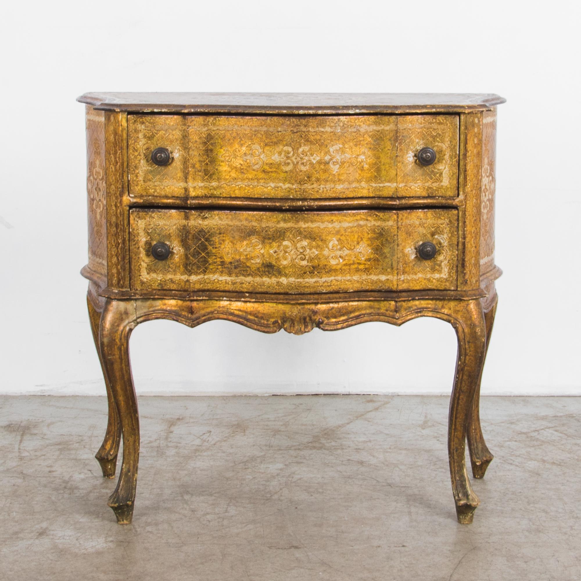 This gilded wooden chest of drawers was made in Italy in the 1960s. Elegantly aged, a refined shape is contrasted with a textured patina and elaborate carved ornament.

A set of serpentine double drawers sits atop slender cabriole legs, the fluid