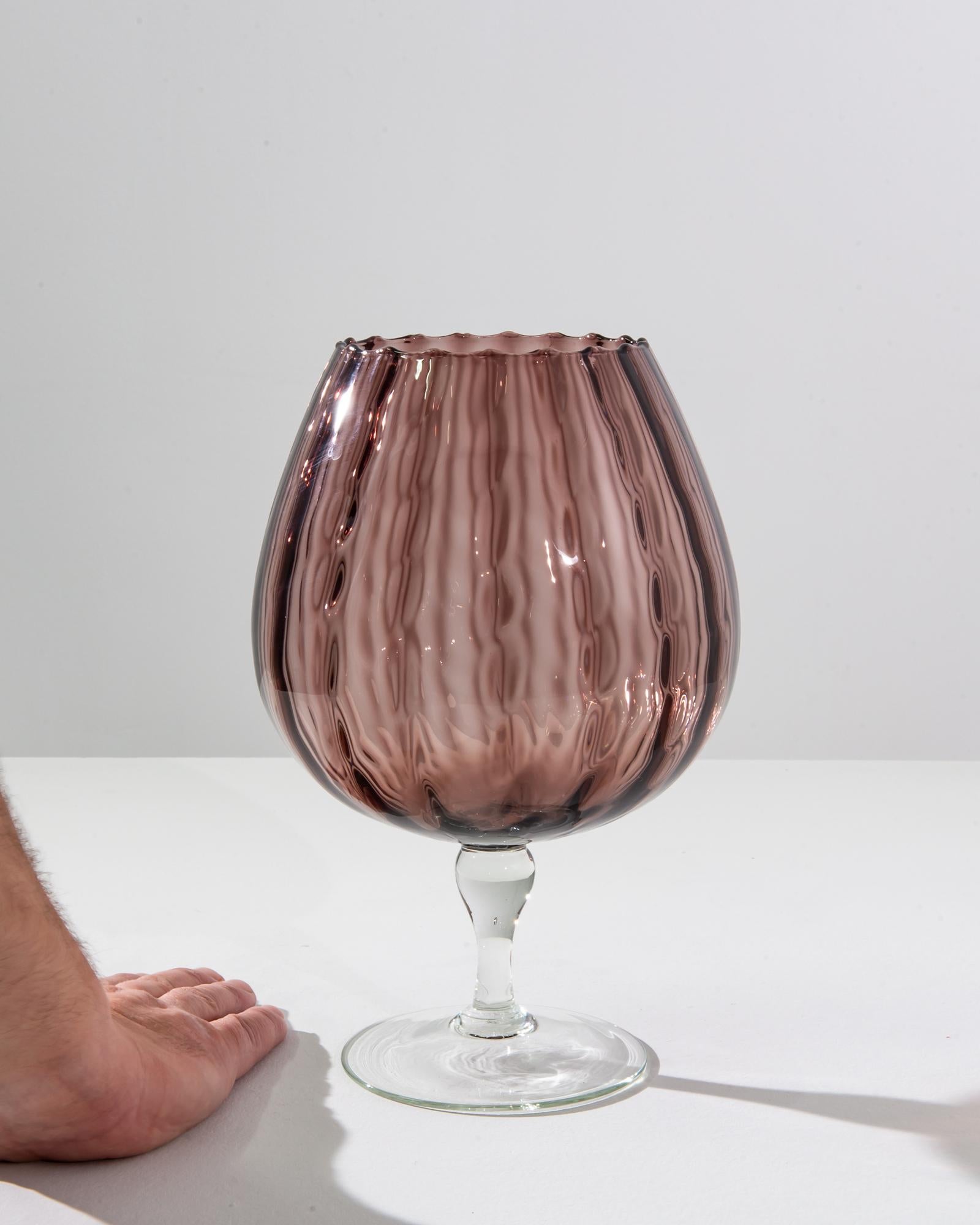 Elevate your home décor with this exquisite Italian glass goblet from the 1960s, a true testament to the artistry of the era. The goblet's striking design features a delicate, fluted body with a unique pleated texture, creating a play of light and