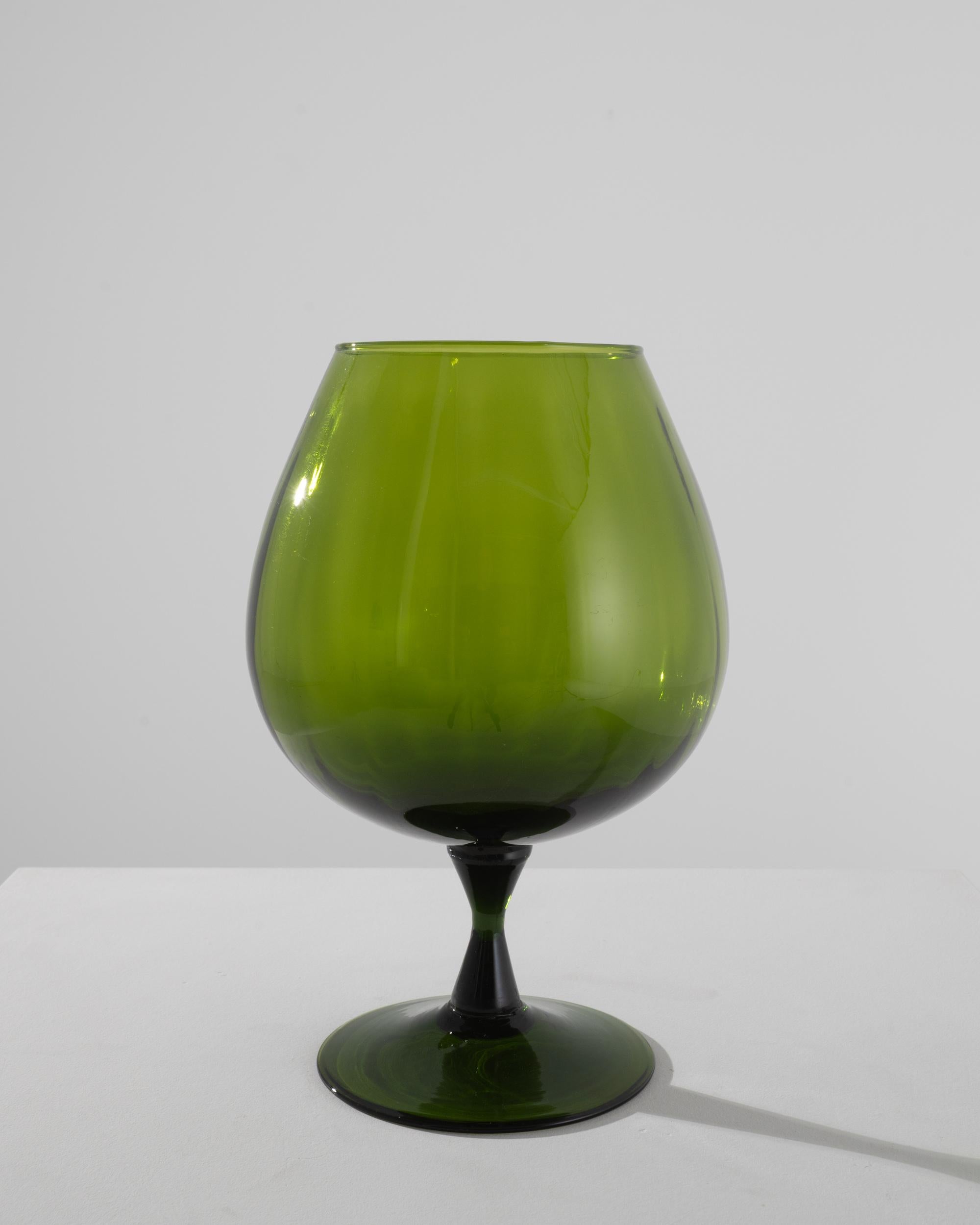 Elevate your table setting with the 1960s Italian Green Glass Goblet, a captivating piece that combines form and function. The goblet features a slender stem that gracefully supports a wide, elegant mouth. Crafted with meticulous attention to