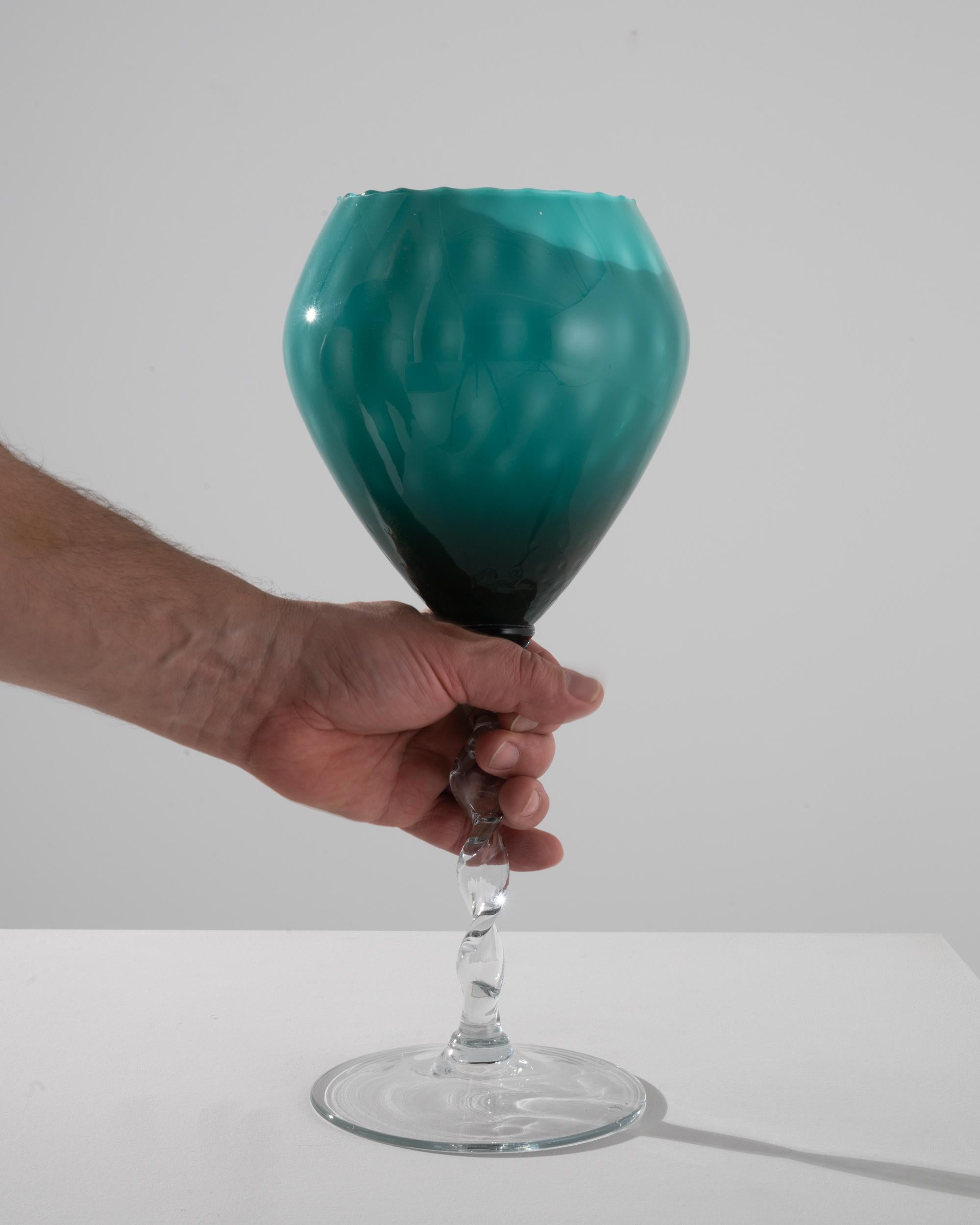 This 1960s Italian Green Glass Goblet is a striking exemplar of vintage charm and elegance. The goblet's enchanting emerald hue is reminiscent of the lush Italian countryside, inviting a touch of nature's serenity into your home. Its unique