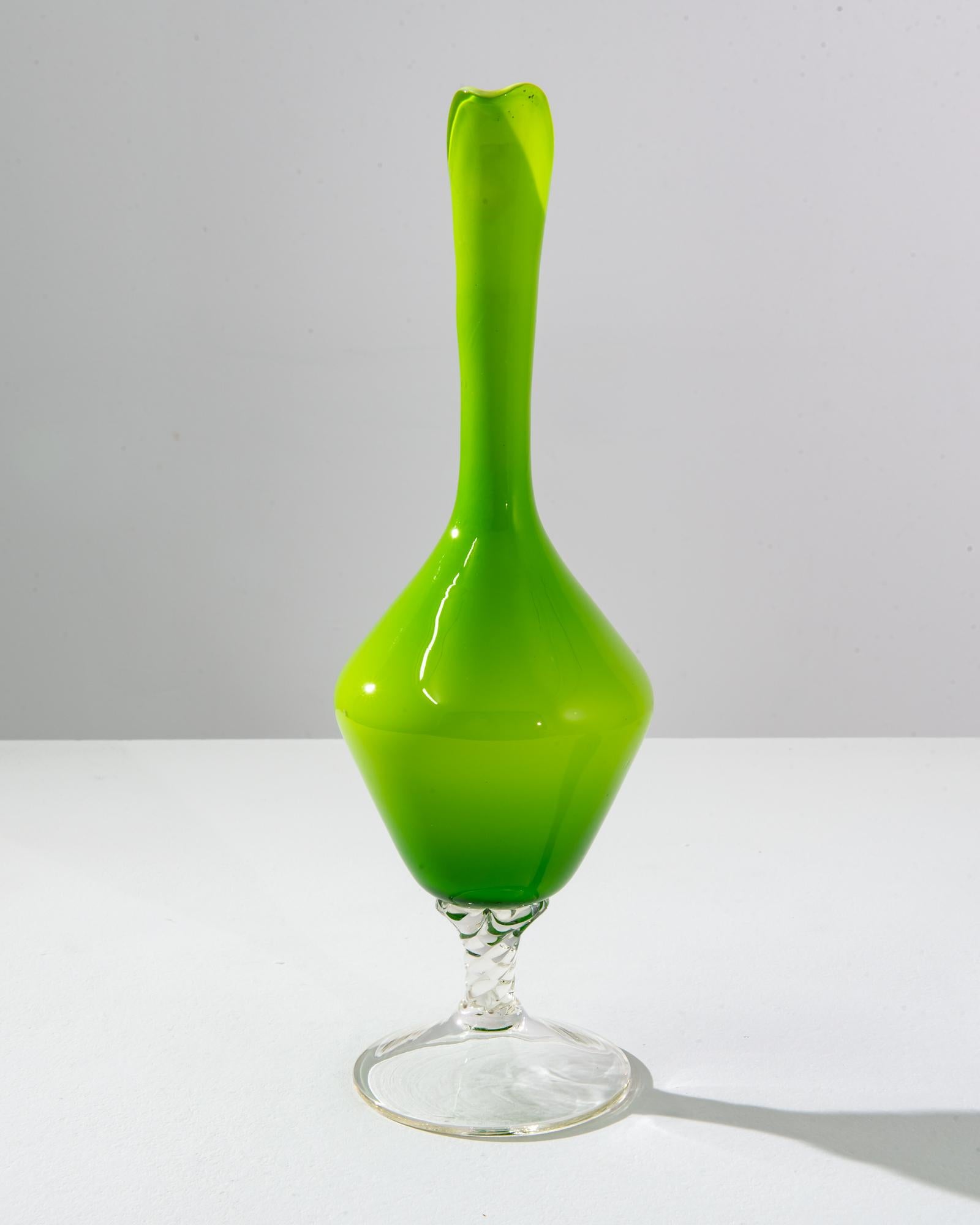 This vibrant 1960s Italian green glass jug is a splendid example of the bold and expressive design ethos of the era. Its luminous lime green body draws the eye, evoking the fresh zest of citrus and the vivacity of springtime. The jug is crafted with