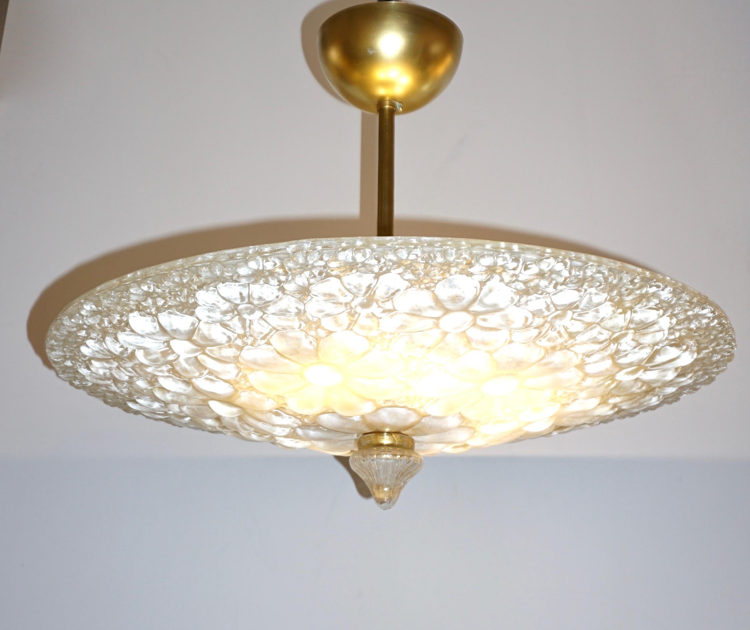 This modern Art Deco design light fixture with brass hardware features a distinctive bowl with a shallow dome form in ivory Murano glass worked with the scavo technique on the inside and overlaid on the outside with embossed petal starburst floral