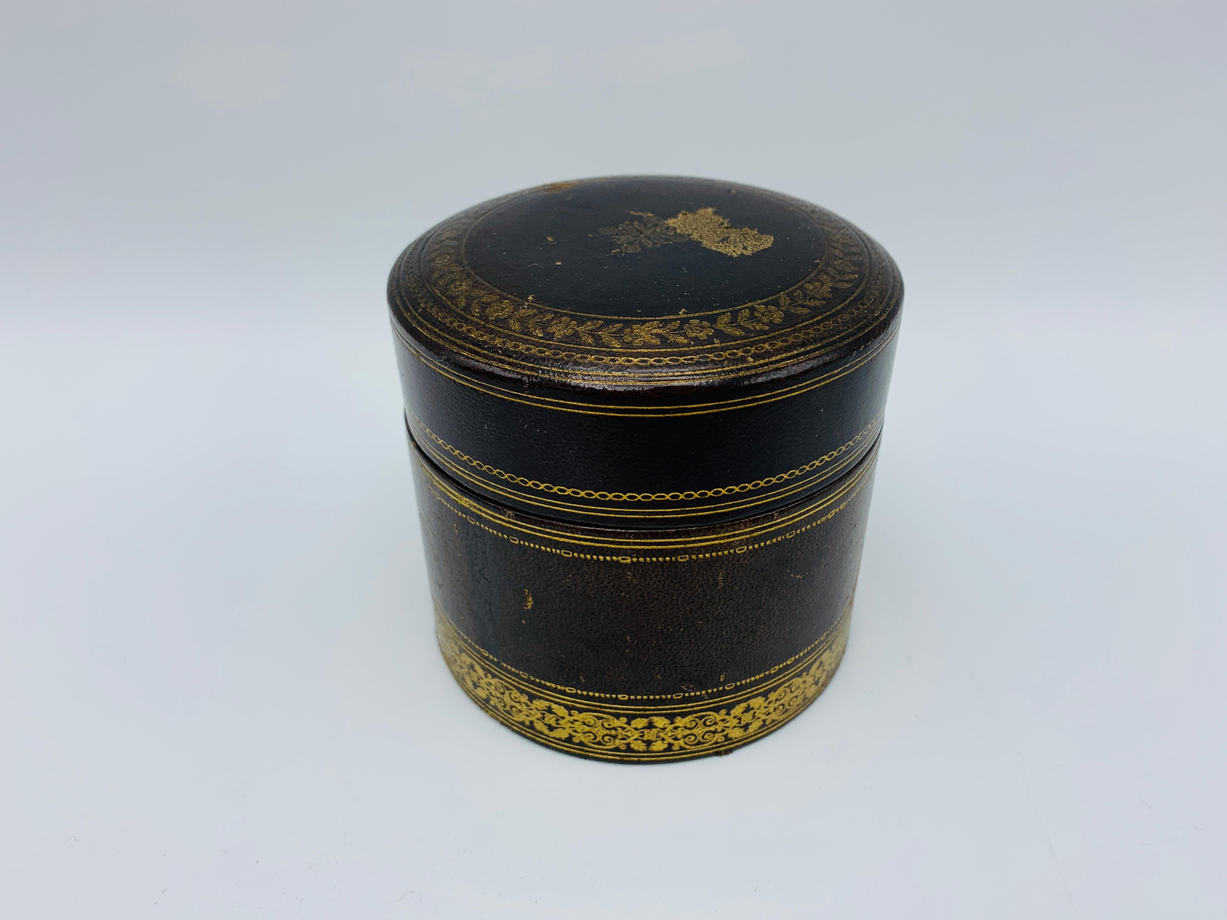 Listed is a beautiful, 1960s Italian leather lidded box. The piece has a deep brown leather exterior, with a gold filigree design. The interior is a deep purple, with a removable divider - perfect in a dining setting to hold toothpicks. Marked 'Made