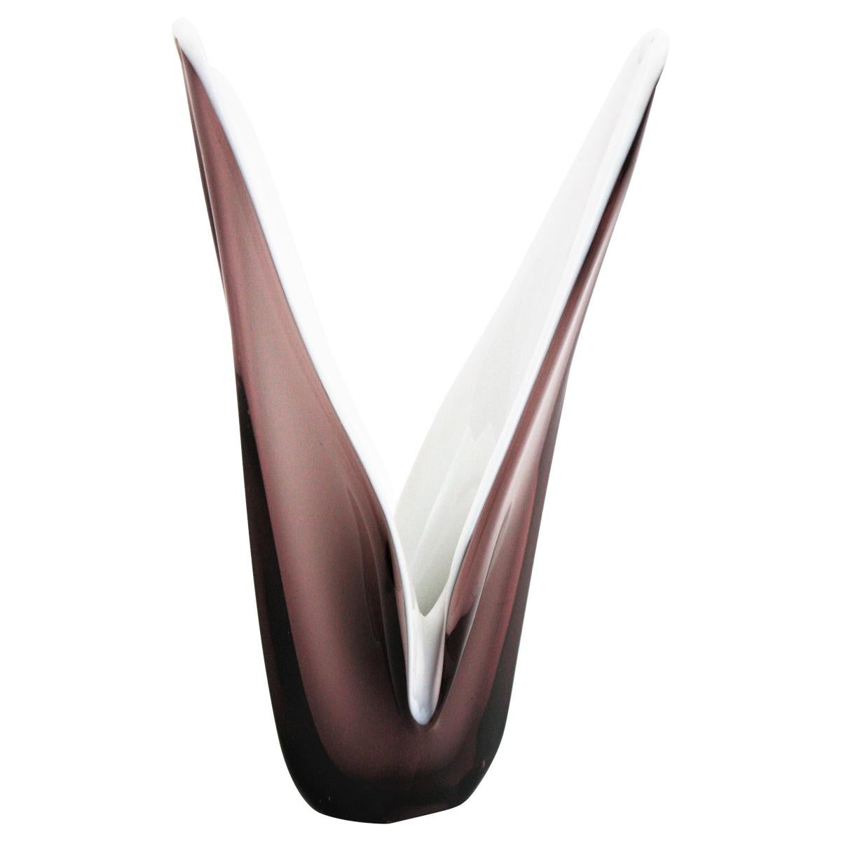 Jarrón o centro de mesa escultórico de cristal de Murano en tonos morados y vidrio blanco leche, Italia, años 60.
Utilizando la técnica Sommerso, la parte interior está realizada en vidrio opalino y la parte exterior es de vidrio lila / morado, más