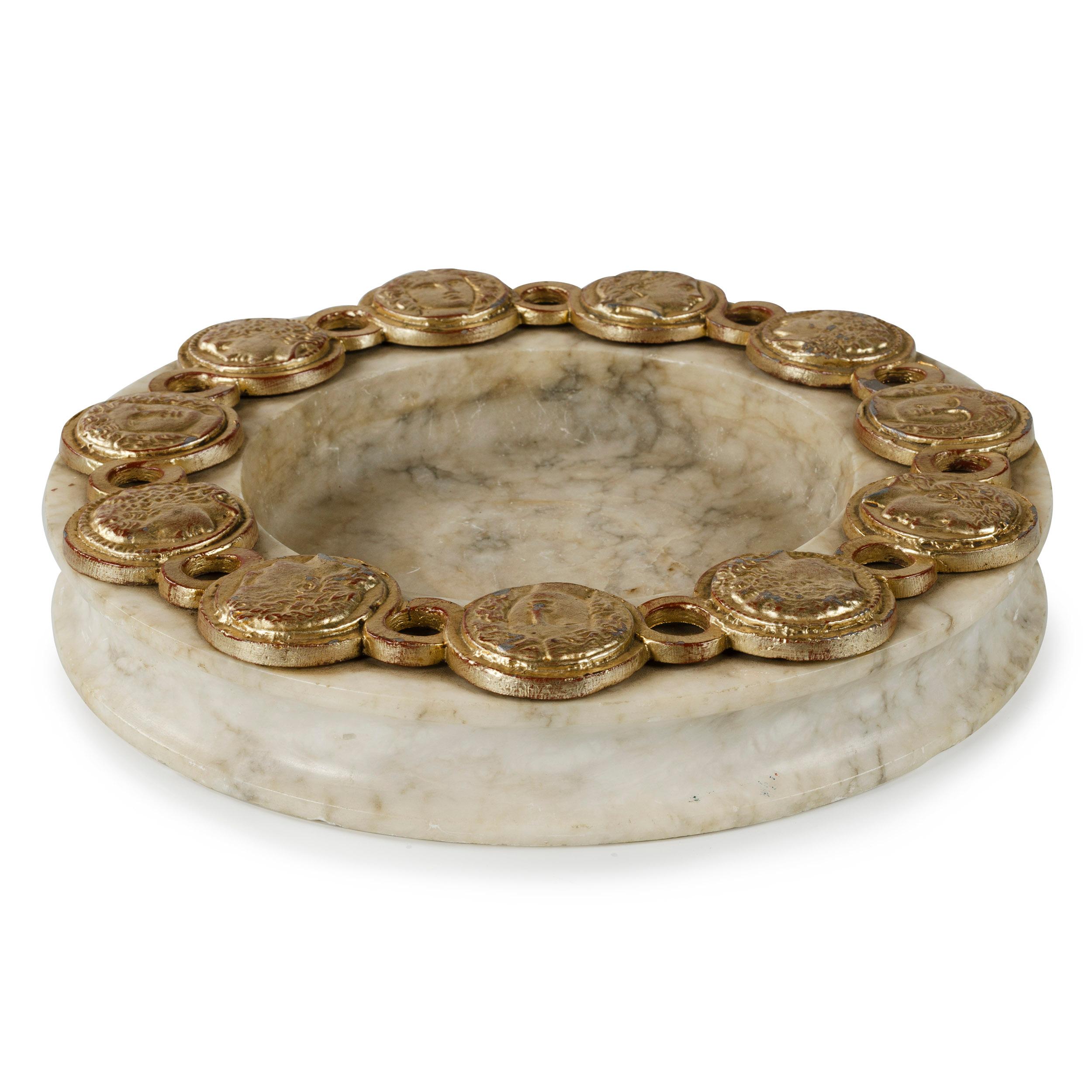 A Palladio marble ashtray encircled with gold painted cast aluminum coins, representing Greek and Roman figures.