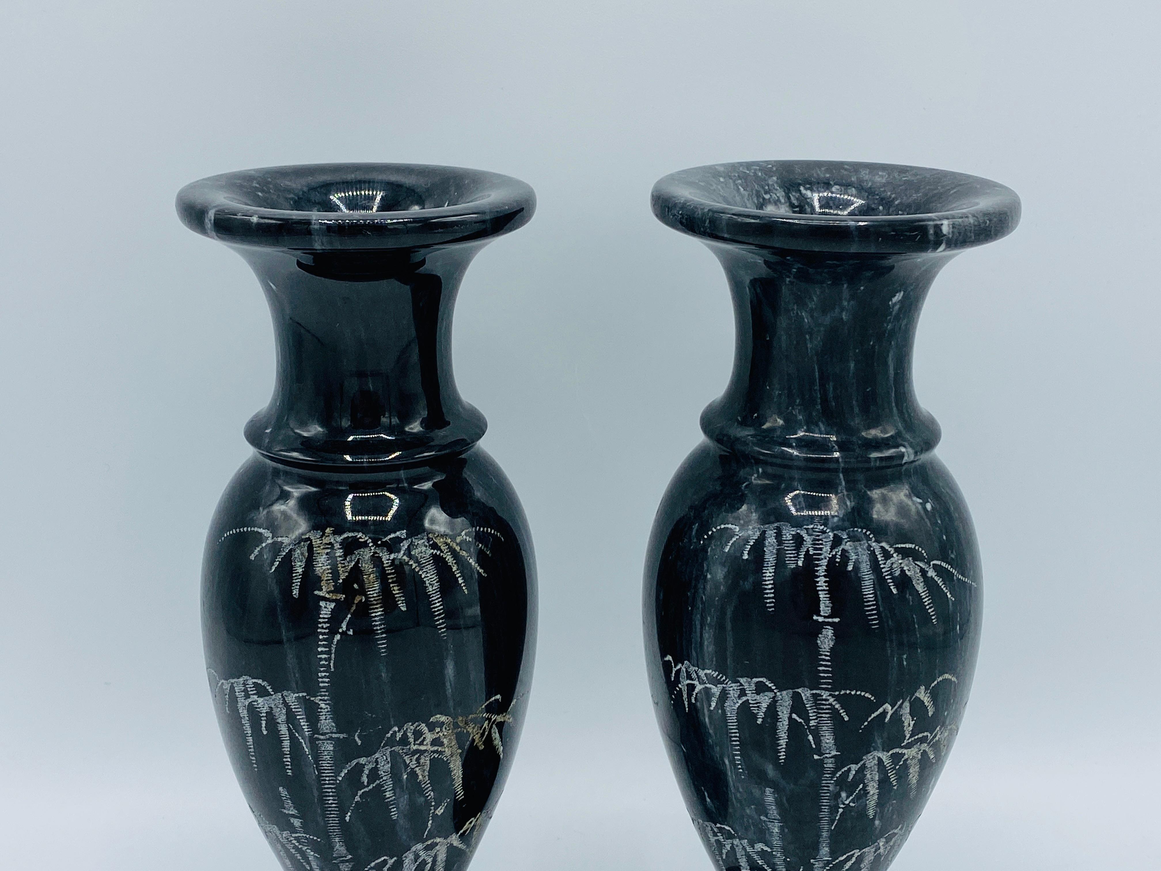 Listed is a stunning, pair of 1960s Italian marble vases. The pair are primarily black with white veining and a bamboo motif etched along one side of each. Heavy, weighing 4.7lbs.