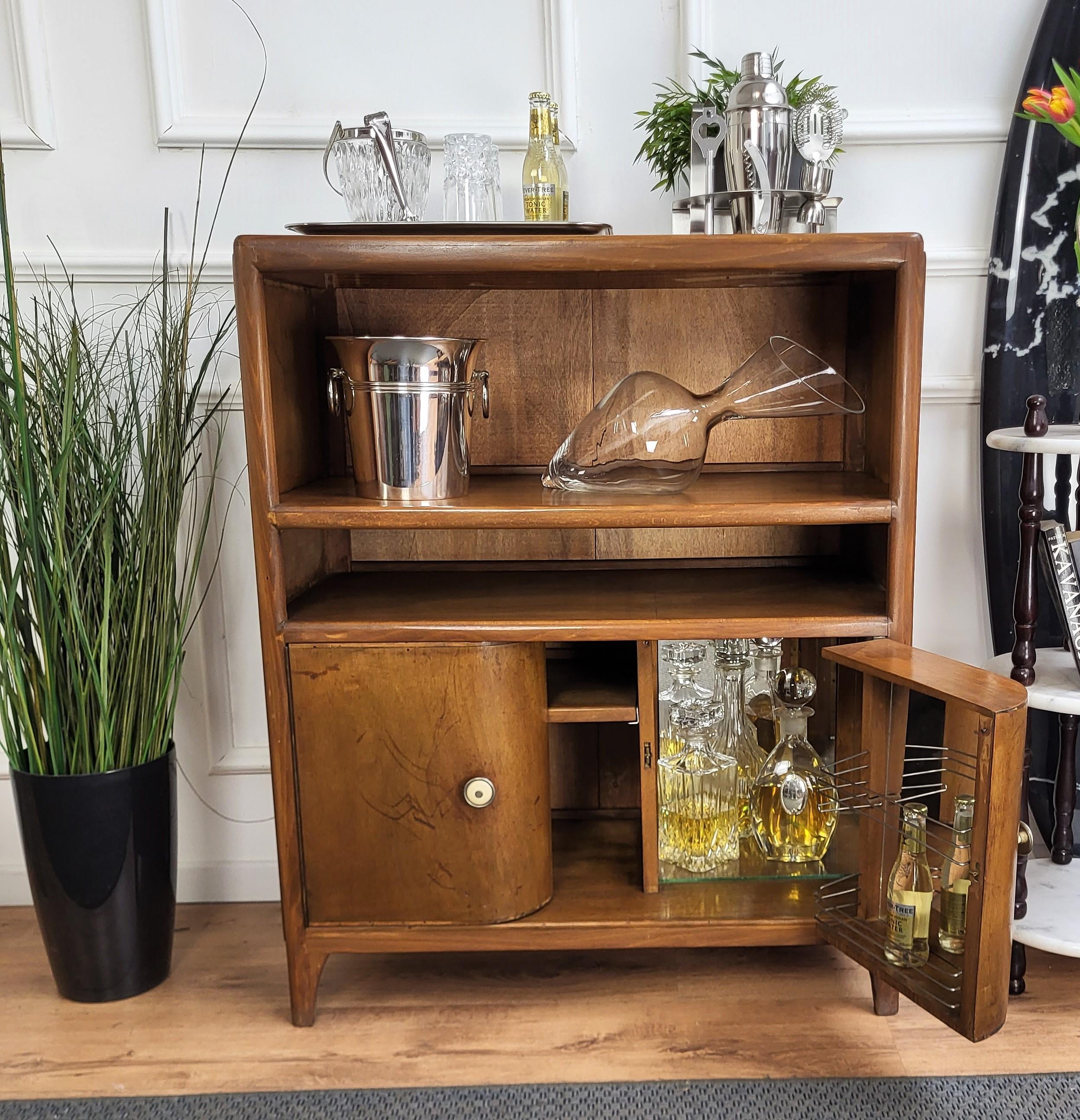 Typical Italian Mid-Century Modern liquor dry bar cabinet, with its greatly designed edges, frames and details in beautiful wood, this piece has two upper shelves and 2 bottom side doors with beautiful handles and mirror interior on the right side.