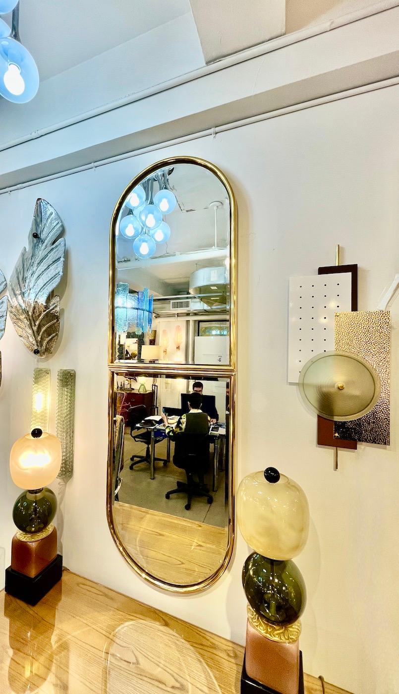 Deux miroirs combinés de style Art of Vintage italien, fabriqués à la main, avec un élégant cadre en laiton au sommet arrondi qui renferme un miroir détaché créant un effet de flottement.
La plaque de miroir se termine par un bord arrondi biseauté