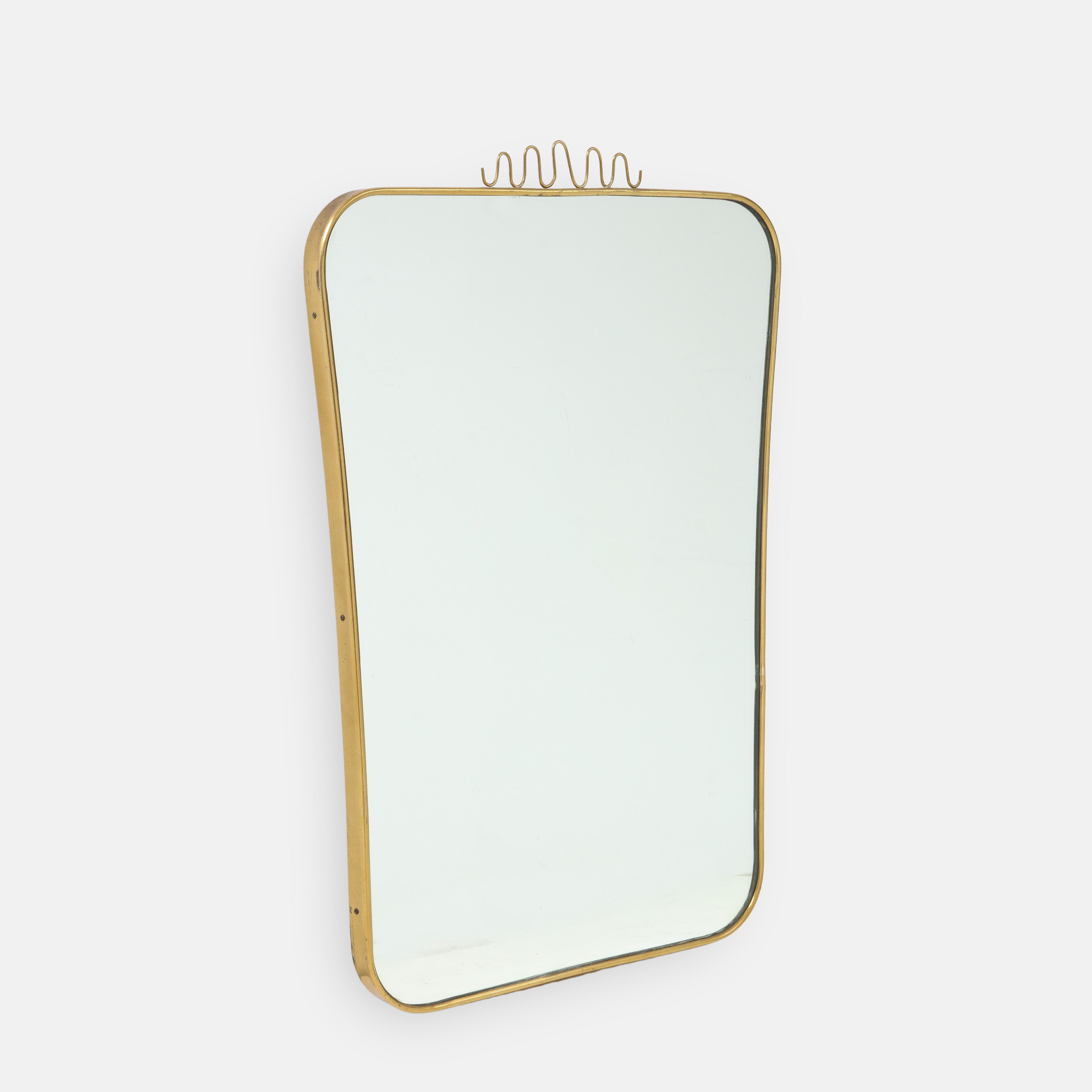Elegant modernist shaped brass wall mirror with lovely decorative brass element on central top, Italy, 1960s. This charming midcentury mirror illustrates in its playful decoration the Italian Novecento design characteristic of this period. The
