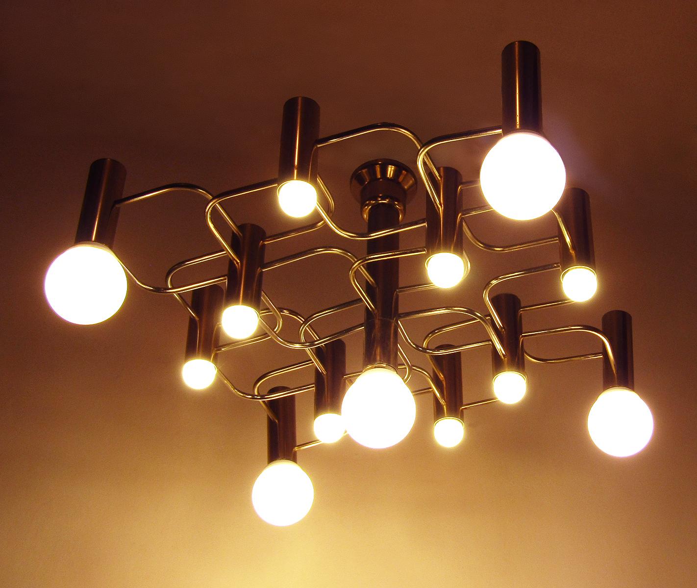 An original 1960s modernist chandelier in brass by Gaetano Sciolari.

It has thirteen individual lights. Each bulb holder allows for large, decorative bulbs. A combination of sizes can also be used, to stellar effect. 

With a height of 48cm it