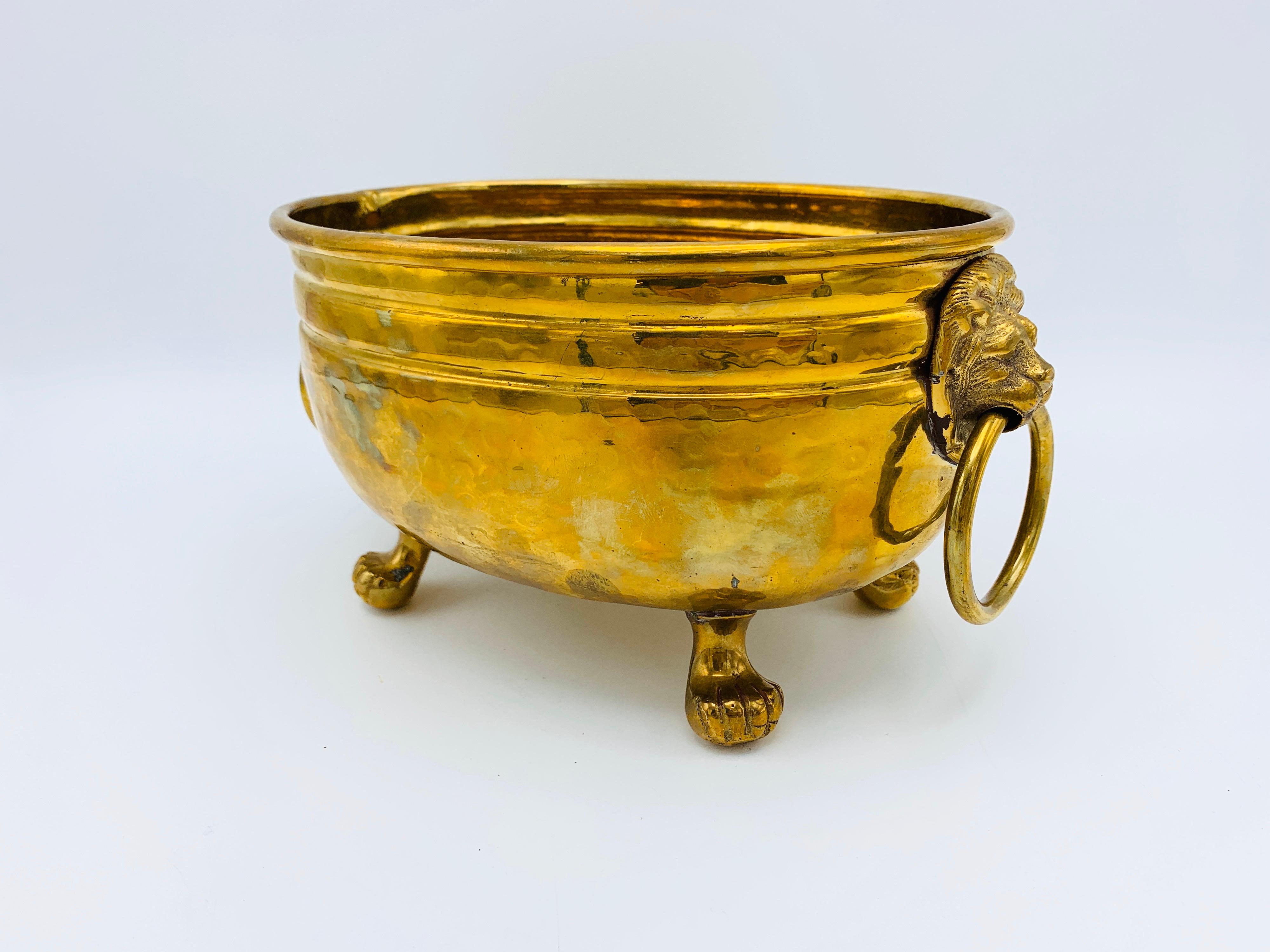 Listed is a stunning, 1960s Italian Mottahedeh hammered brass cachepot planter with lions head handles and clawfeet. Incredible piece with a beautiful polished brass. Heavy, weighing 2lbs.
