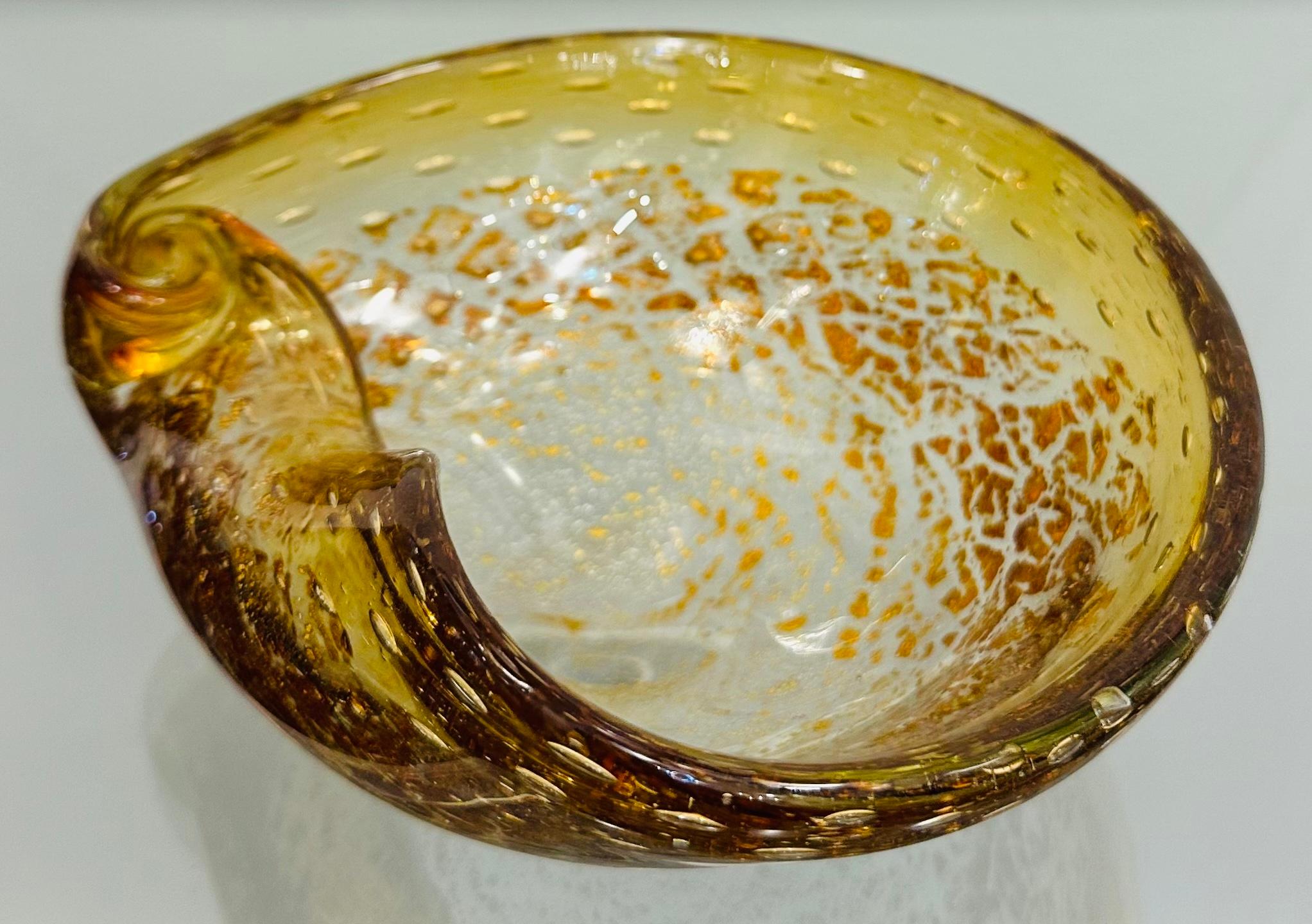 1960s Italian Murano glass bowl or dish formerly known as an ashtray. Handblown in gold and clear glass with gold inclusions circling over the whole exterior which  grow larger towards the edge.  A circular rose bud shape has been blown into the