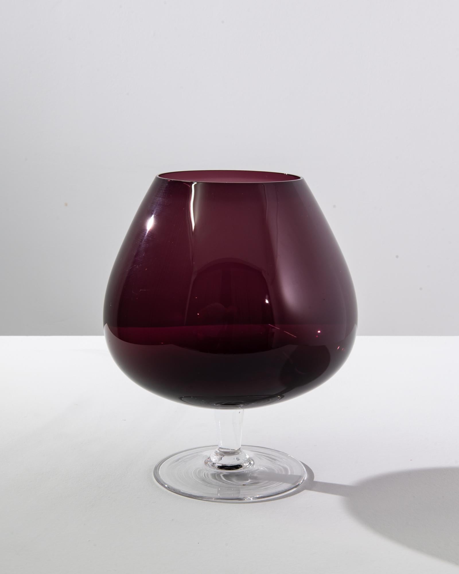 Elevate your dining experience with this stunning Italian purple glass goblet from the 1960s, a time when craftsmanship met the peak of elegance. The deep burgundy hue of the glass captures the essence of vintage luxury, reminiscent of a fine wine,