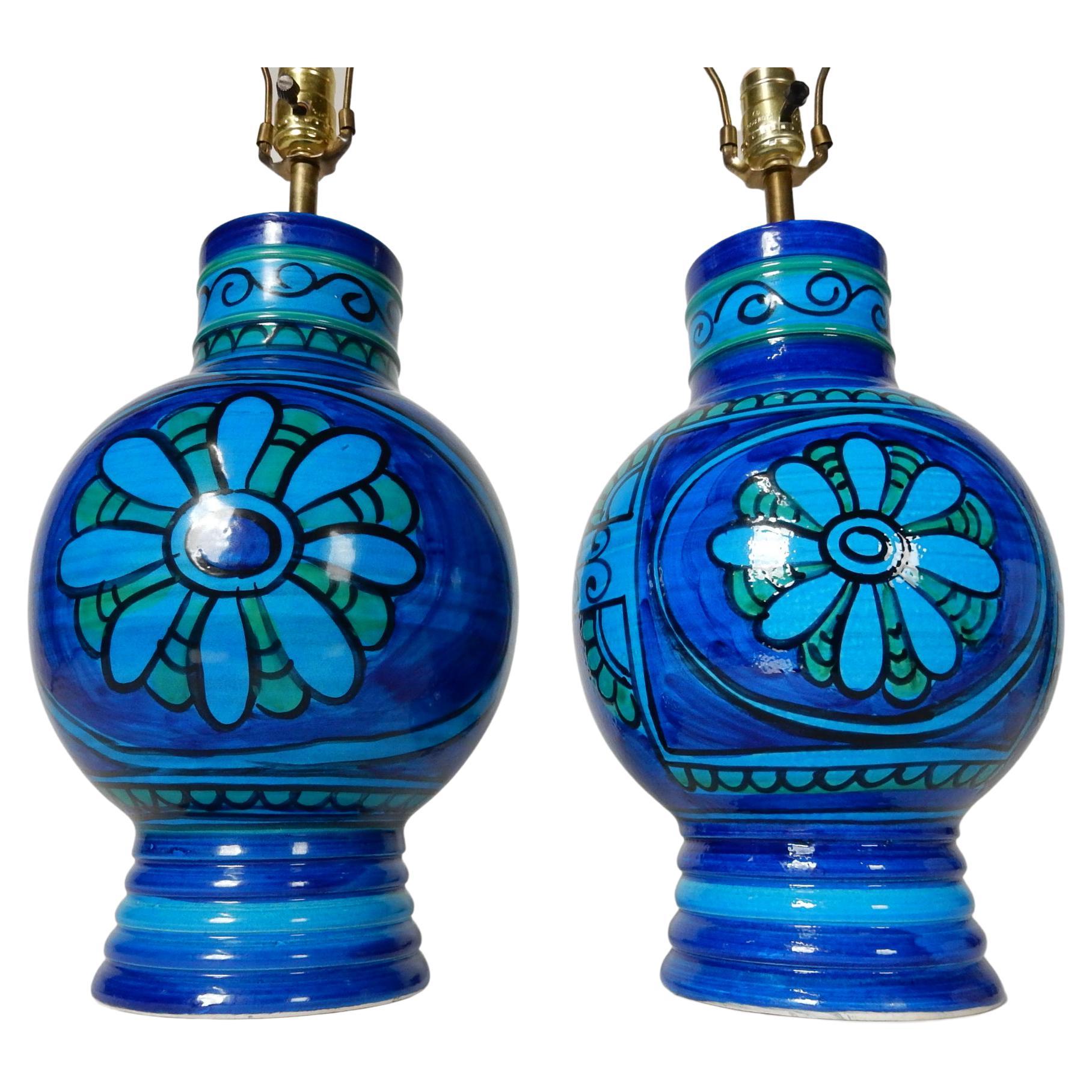 Lovely pair of mid century era table lamps.
Hand painted floral design in Rimini blue.
We believe them to be an Italian artist lamp in
the style of Bitossi. 
Circa 1960's with original wiring. Condition is flawless.