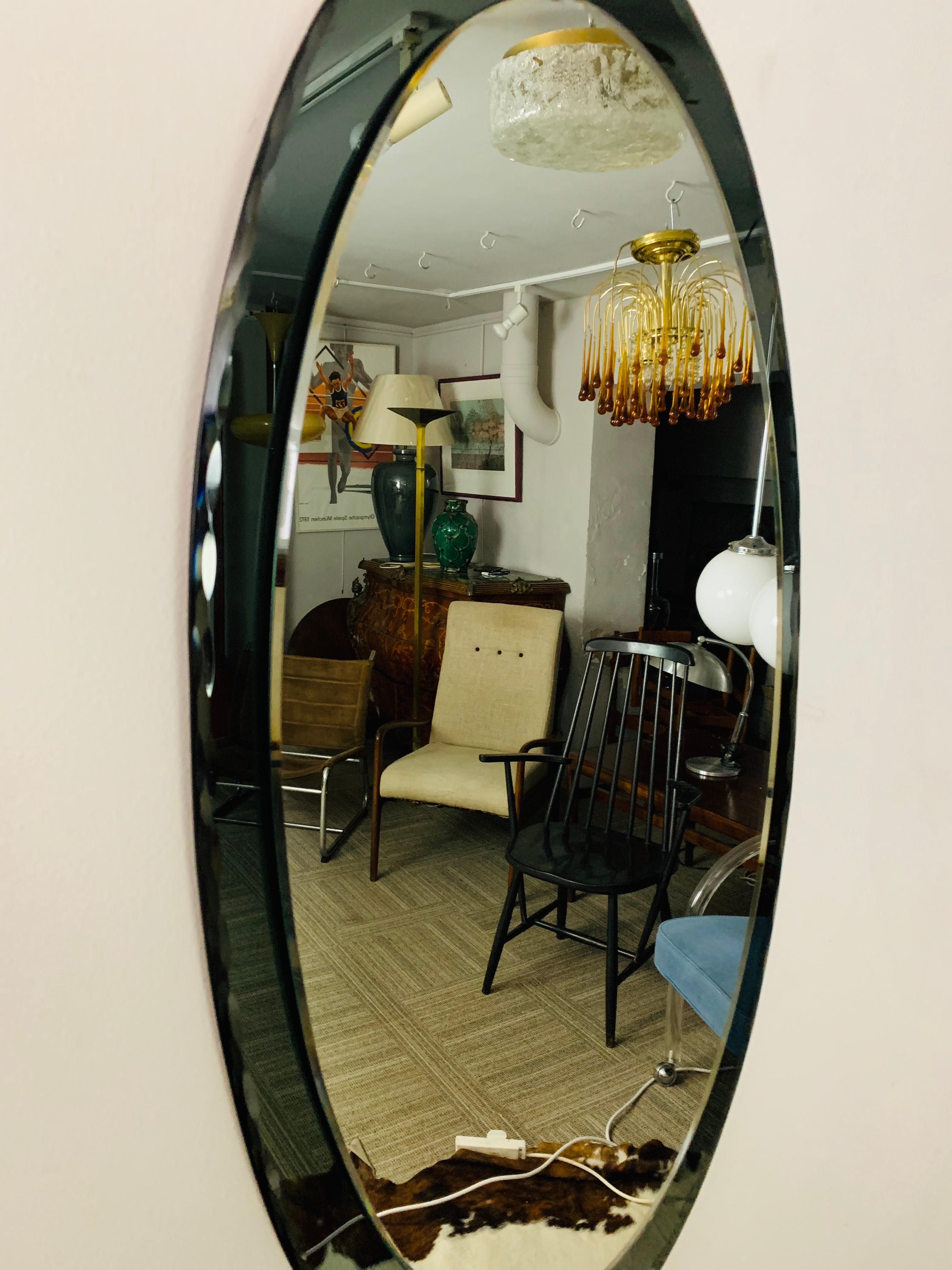 A 1960s Italian scalloped and beveled edge hanging wall mirror in the style of Fontana Arte. The clear glass mirror sits on a green smoked scalloped feature backplate. The reverse of the mirror has been covered in cork to avoid any damage to the