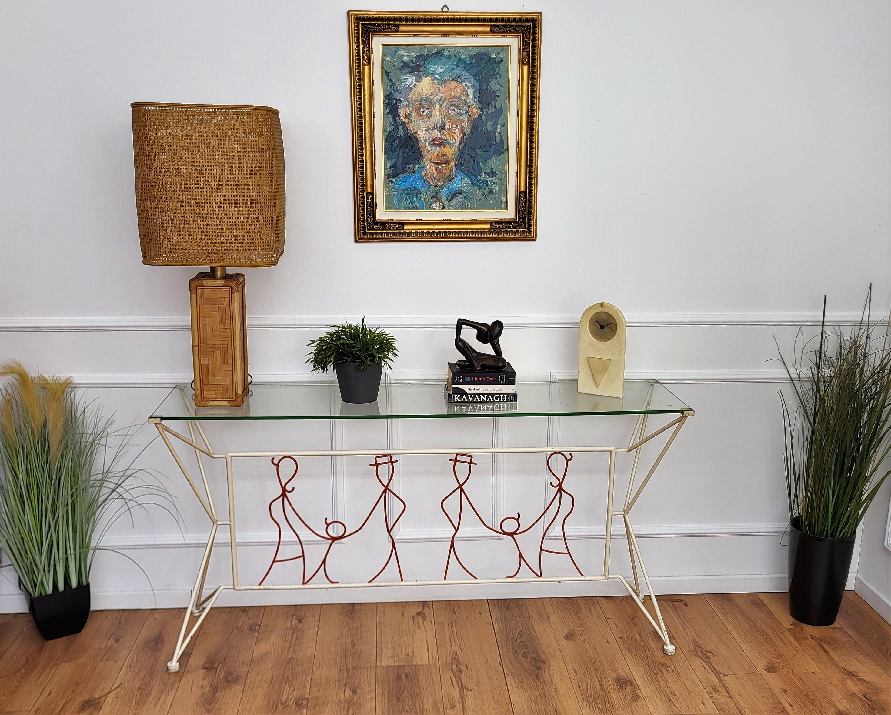 A stunning handcrafted Italian iron painted console table with a hand-wrought iron base where we have a red painted linear central stylized family portrait with a female, child and male figures holding each-other framed inside a white/cream painted