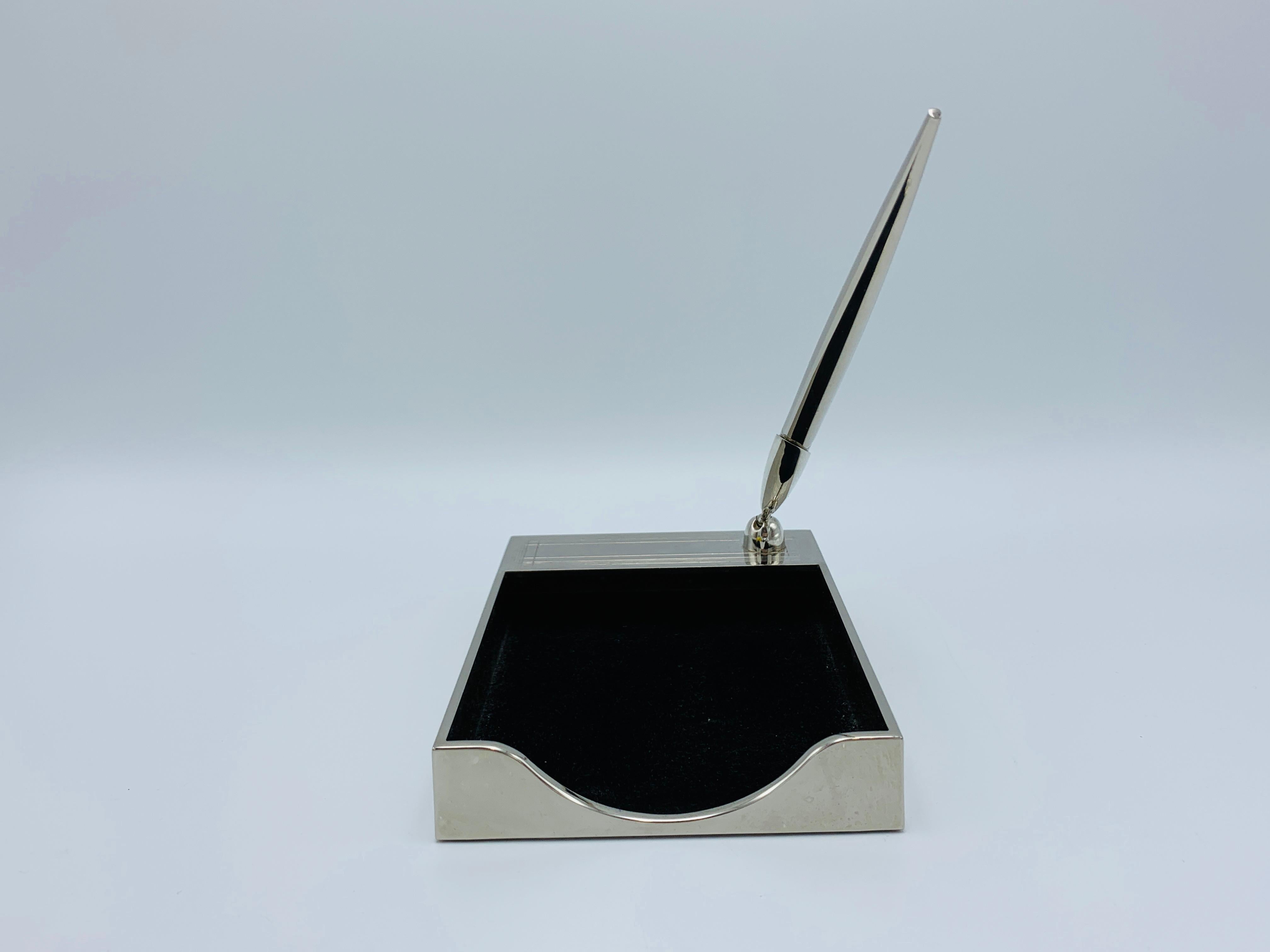 Listed is a stunning, 1960s Italian silver-plate stationary notepad and pen desk set. The piece includes a notepad holder with an attached adjustable pen holder, and matching pen. The piece can hold a standard 4