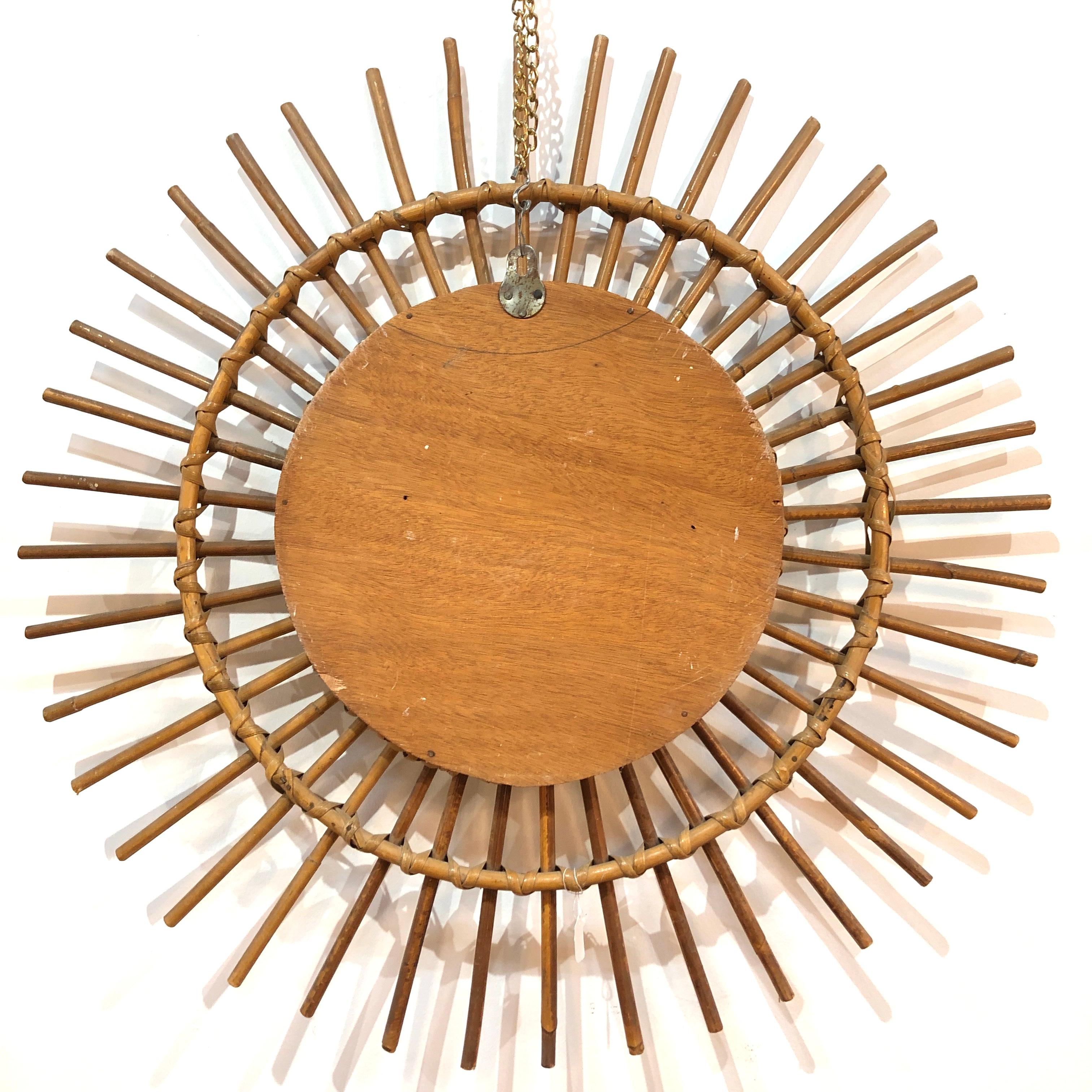 Delightful sun-shaped round mirror in braided rattan and bamboo. Produced in Italy during 1960s.
This beautiful mirror features a double frame with fantastic rattan wicker weaves, the frames are decorated by straight rattan beams.

Sourced in Lyon