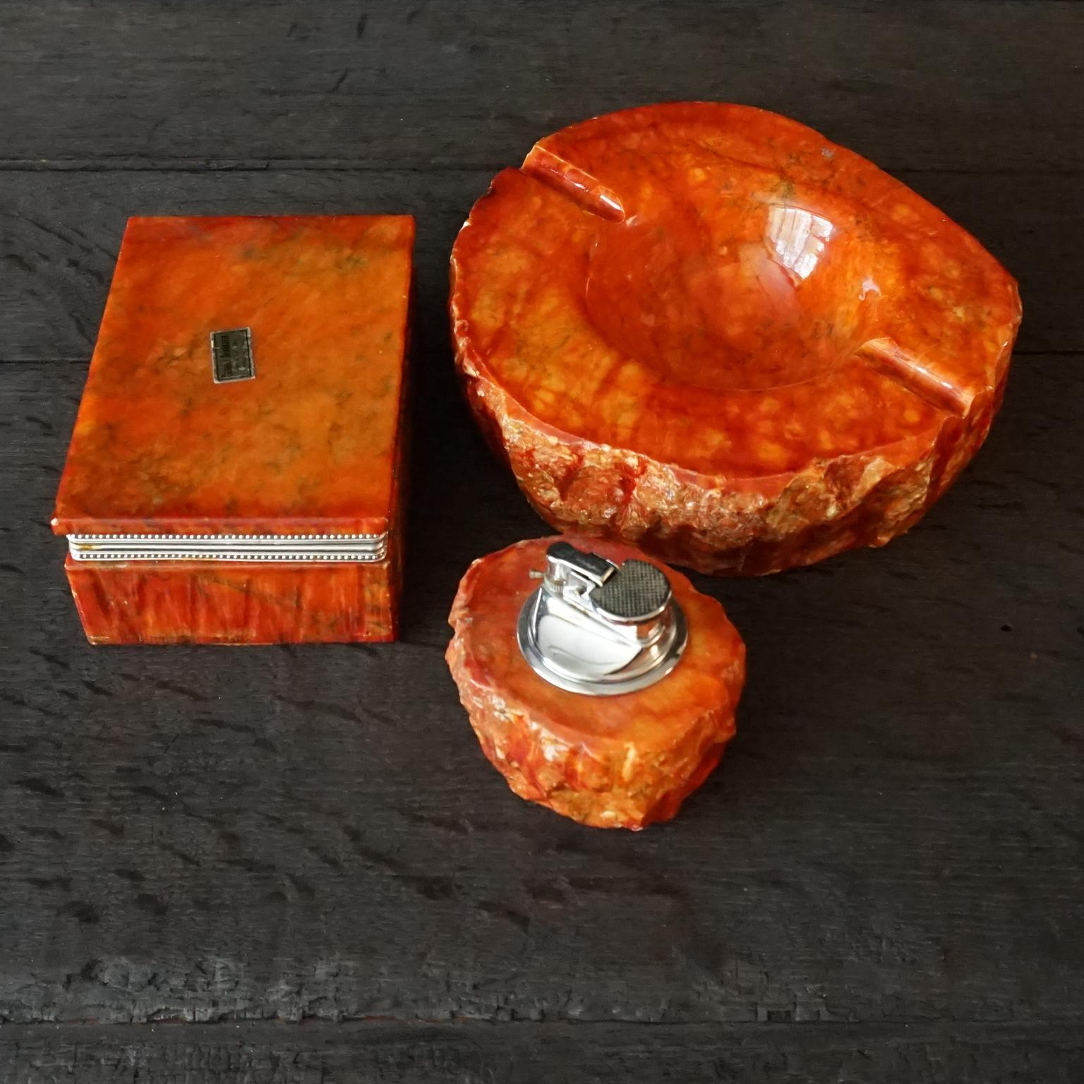 Very decorative 1960s Italian hand carved orange alabaster smoking set by Romano Bianchi.
Consists of a heavy ashtray, also very useful as trinket dish or vide-poche. 
A table lighter (which also fits a wax tea light candle).
And a very pretty