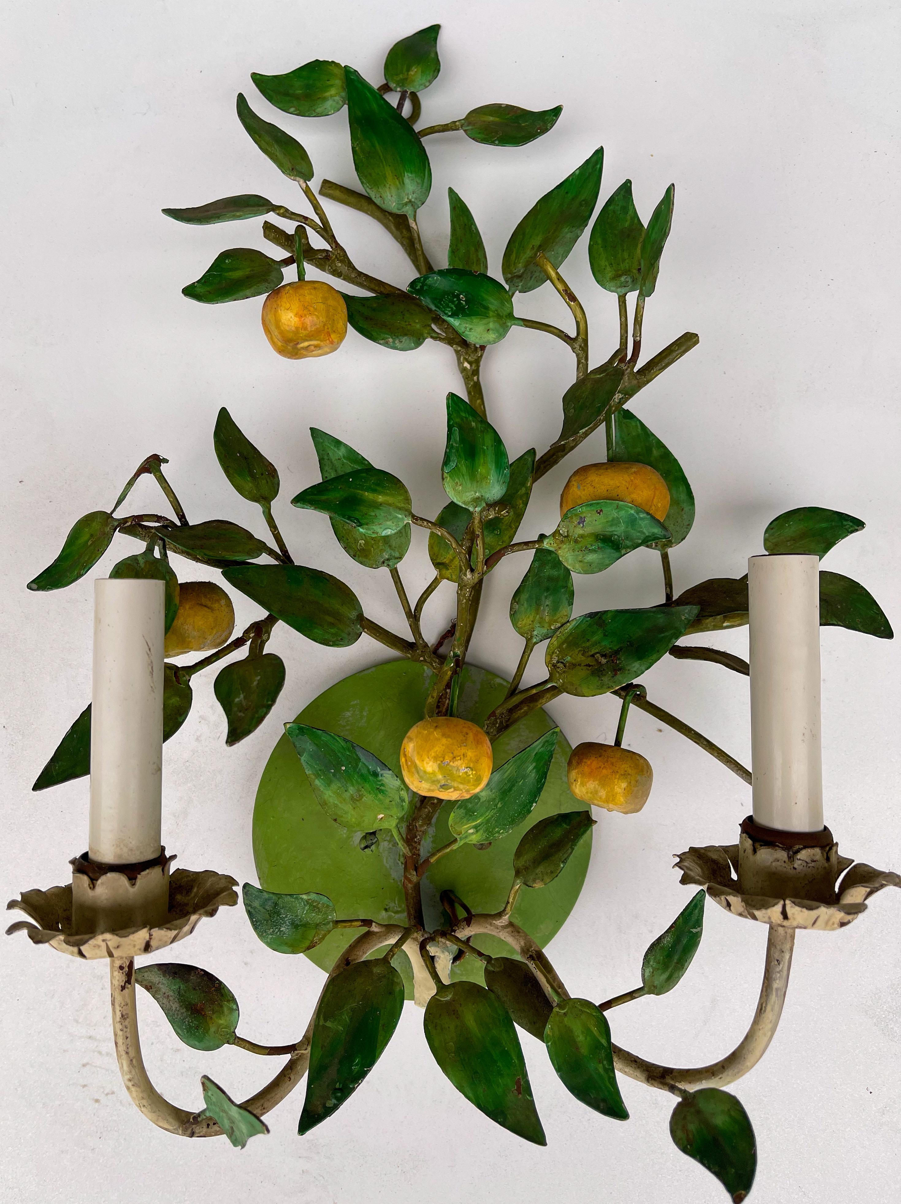 This is a set of Italian toleware fruit and foliate sconces. They are electrified. The yellow fruit appears to be an apple. They do show some age wear to the paint.