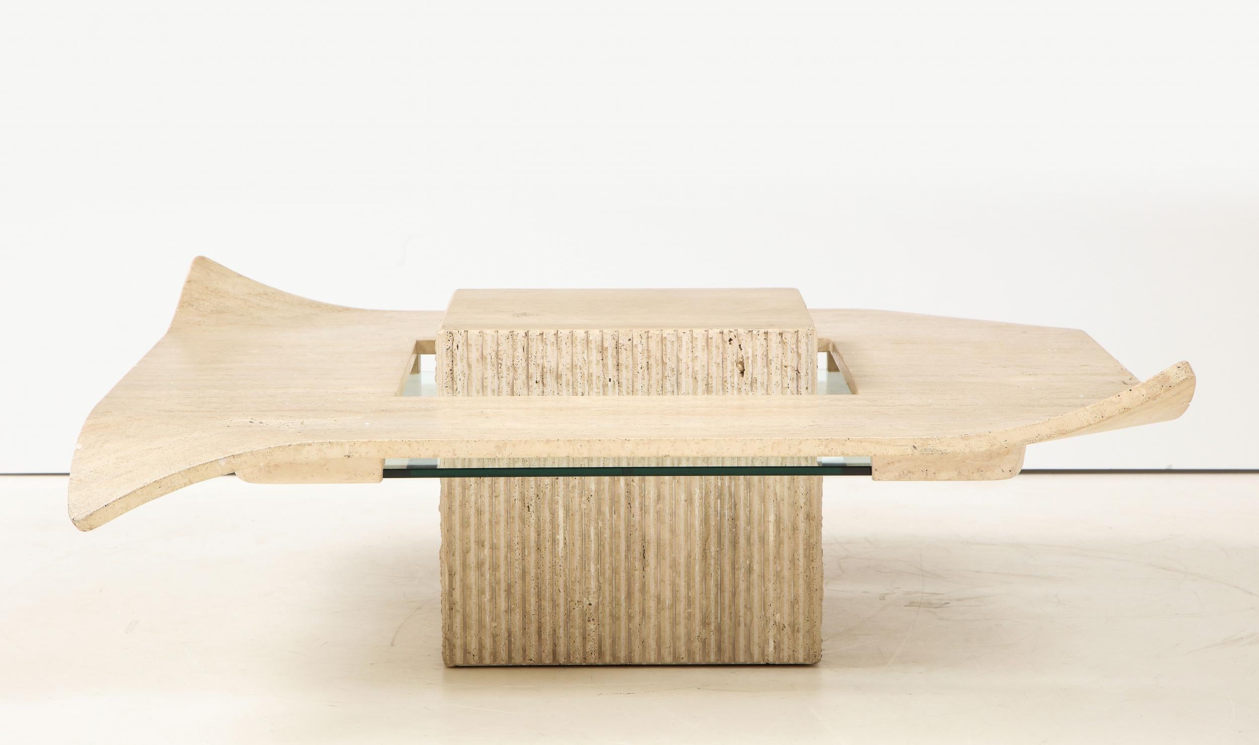 Gorgeous Italian Mid-Century Modern cocktail table. The carved base has a reeded stone detail in a rough finish. The polished travertine top has turned corners in a handerkerchief look reminiscent of the Willy Guhl style. The travertine top is