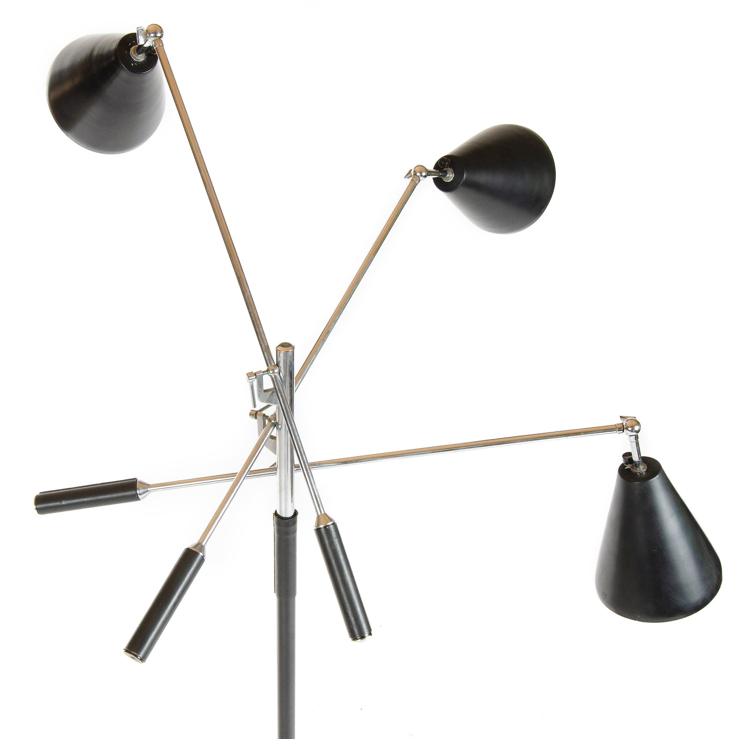 A 'Triennale' floor lamp from the period distributed by Koch & Lowy (NYC) with three chromed fully articulating arms and hand stitched black leather grips supporting (3) conical metal shades. A black and white marble base supports a black