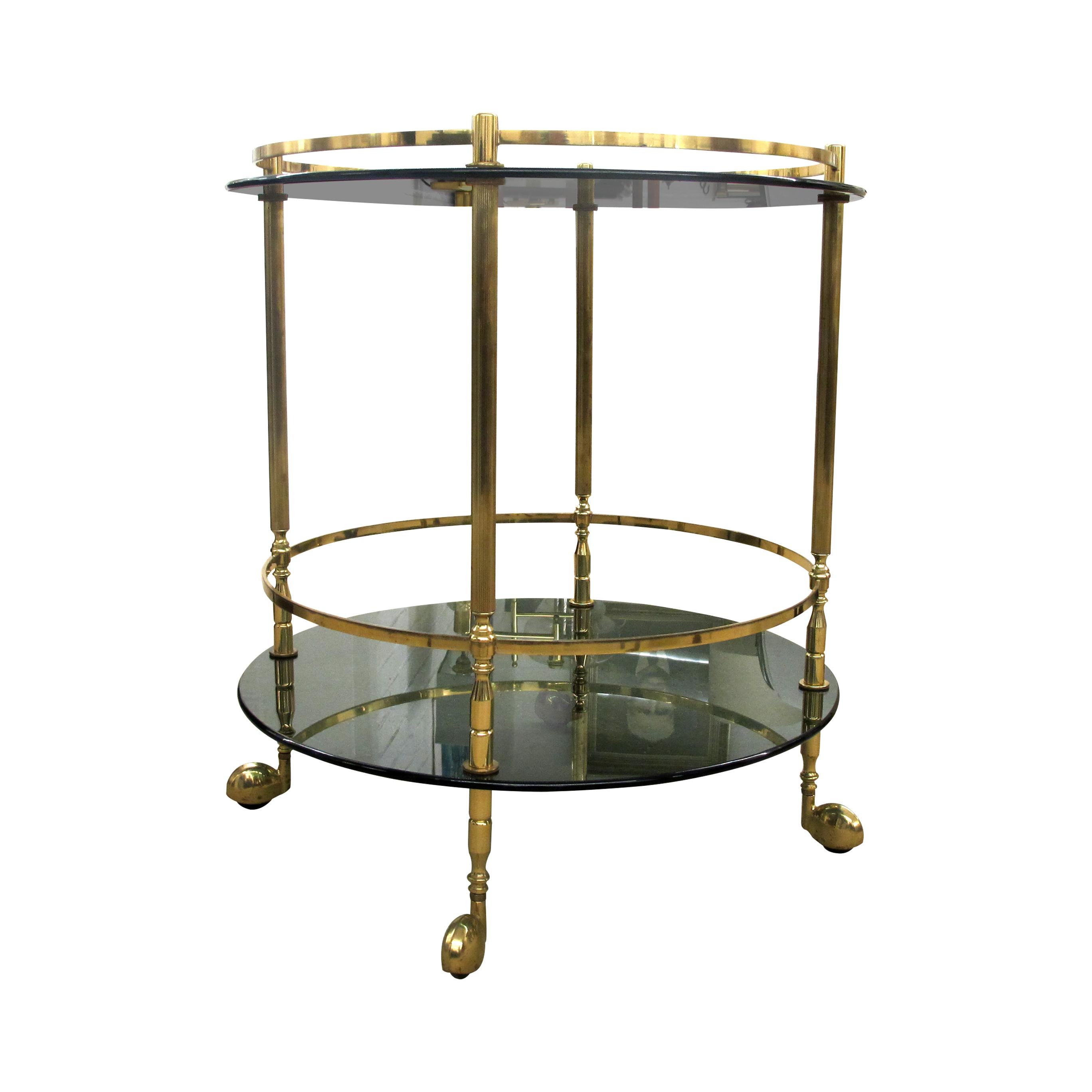 Elegant 1960s Italian two-tier round trolley with its original smoked glass. The bar cart is mounted on 4 brass castors and wheel very well. The trolley is functional and its sleek design will blend in with most of the interiors. 

Size: H69 cm x