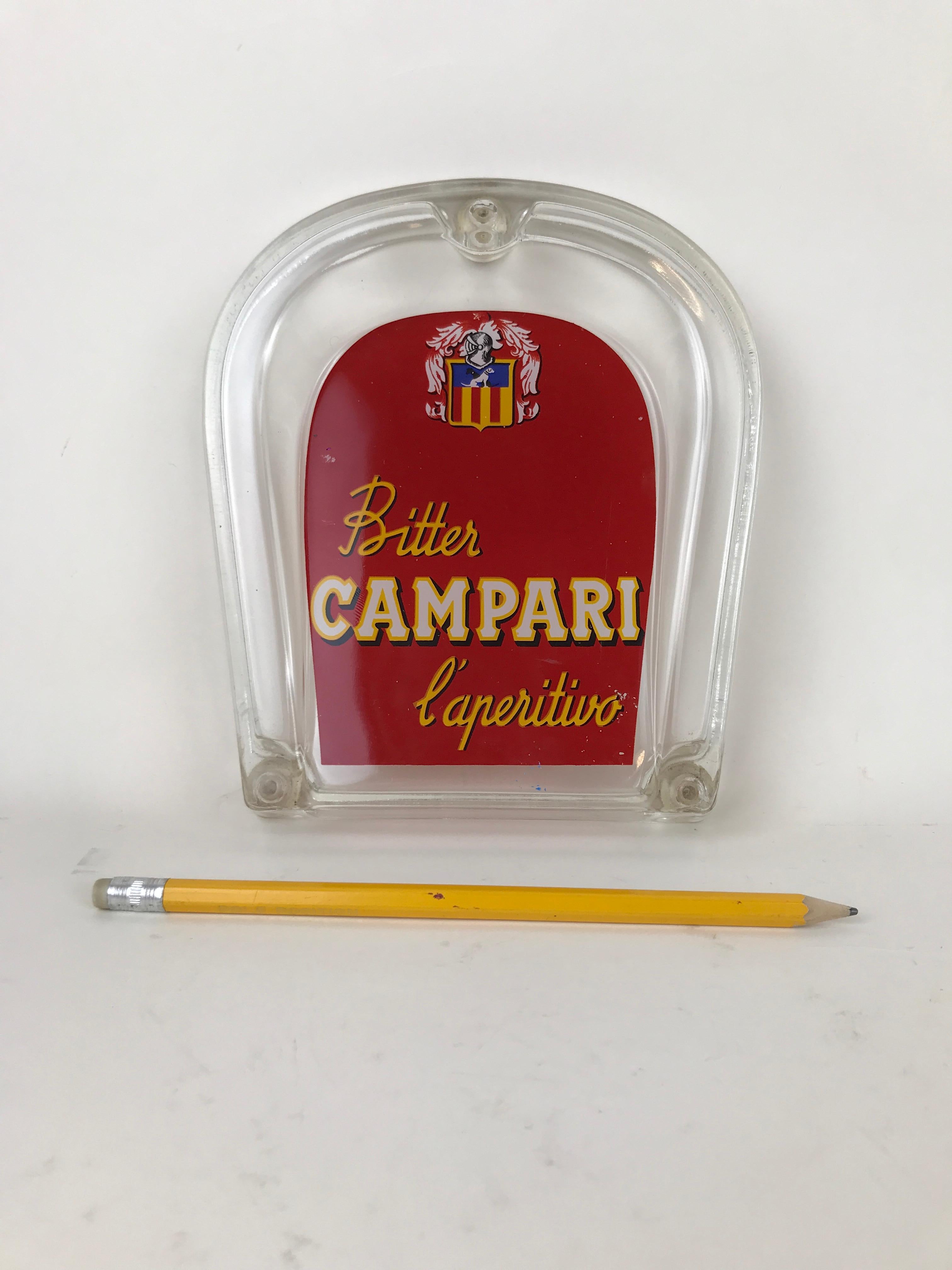 Vintage glass Bitter Campari l'Aperitivo horseshoe shaped money tray in red color made in Italy in the 1960s. 

In the upper part there is a nice coat of arm style decoration.

Collector's note:

Campari is an Italian alcoholic liqueur,