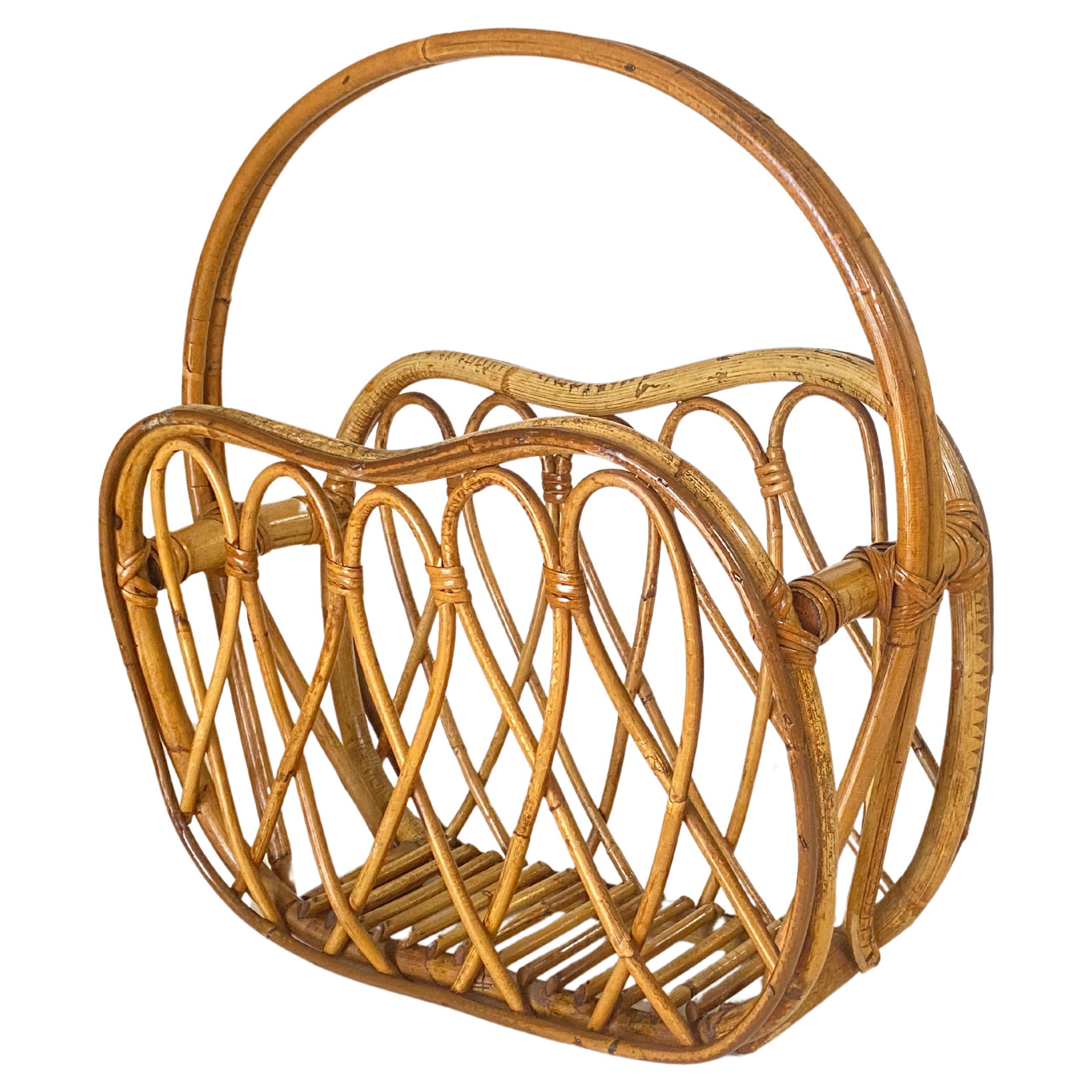 This vintage mid-20th century Italian raised magazine stand with a round handle is handcrafted in natural rattan, beautifully and carefully bent to make an elegant curved design and decor all around. The ease of carrying and moving this piece makes