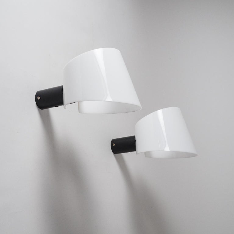 Brilliant pair of Italian wall lights from the 1960s. Minimalist black lacquered tubular base attaches to the wall sporting a white dynamic visor-shaped acrylic diffuser. One original E27 socket with new wiring.