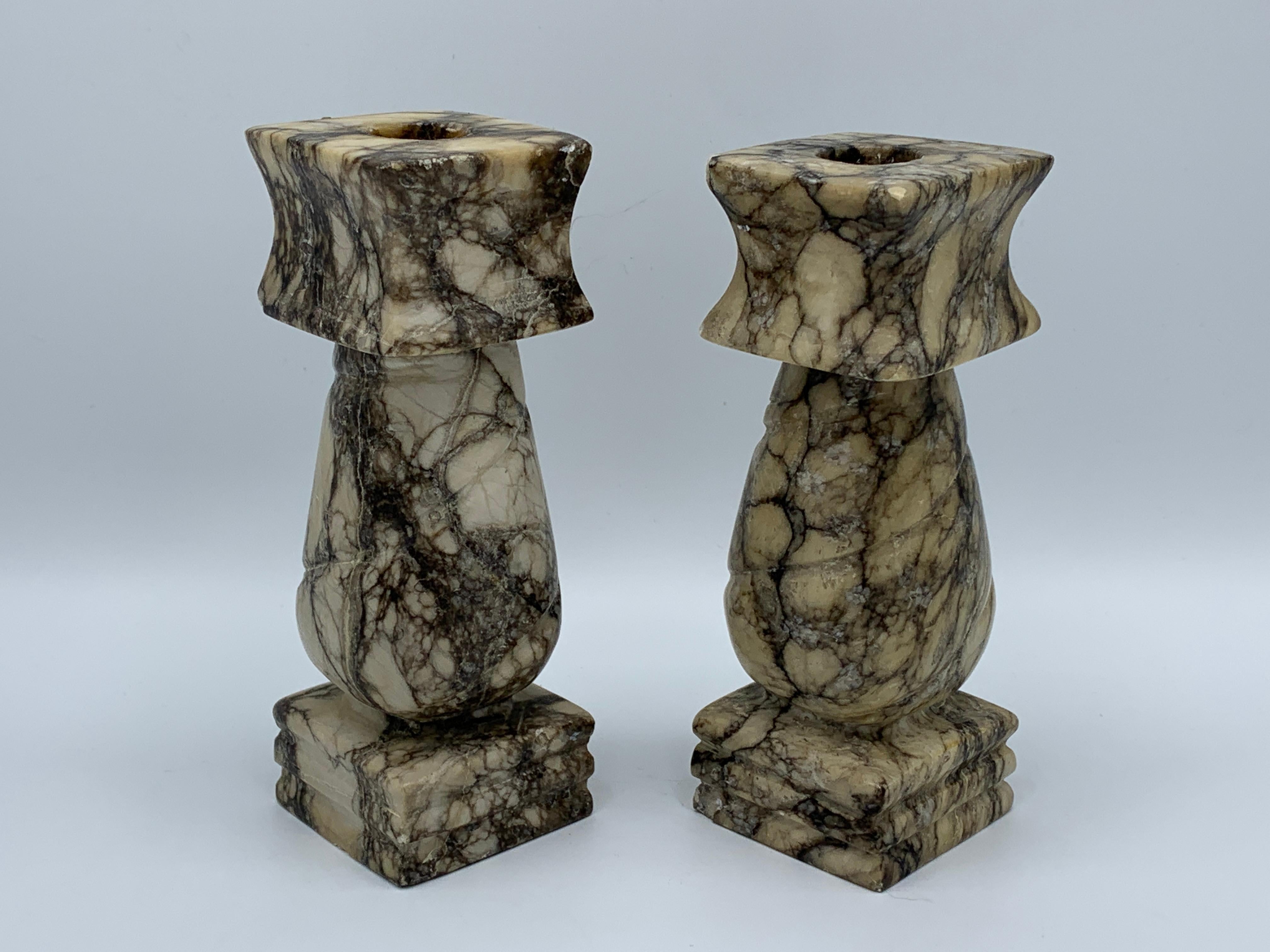 Offered is a beautiful, pair of 1960s Italian marble column candlesticks. The pair are white/beige and black/gray, with allover veining. Heavy, weighing 3lbs for the pair.