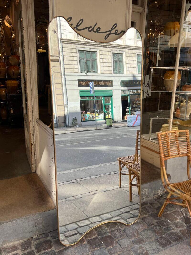 Magnificent Italian midcentury figure mirror from around, in a handsome large design and with a stunningly formed profile.

Noted the gorgeous curved top and base.

The elegant mirror glass is original and this piece stylistically related to the