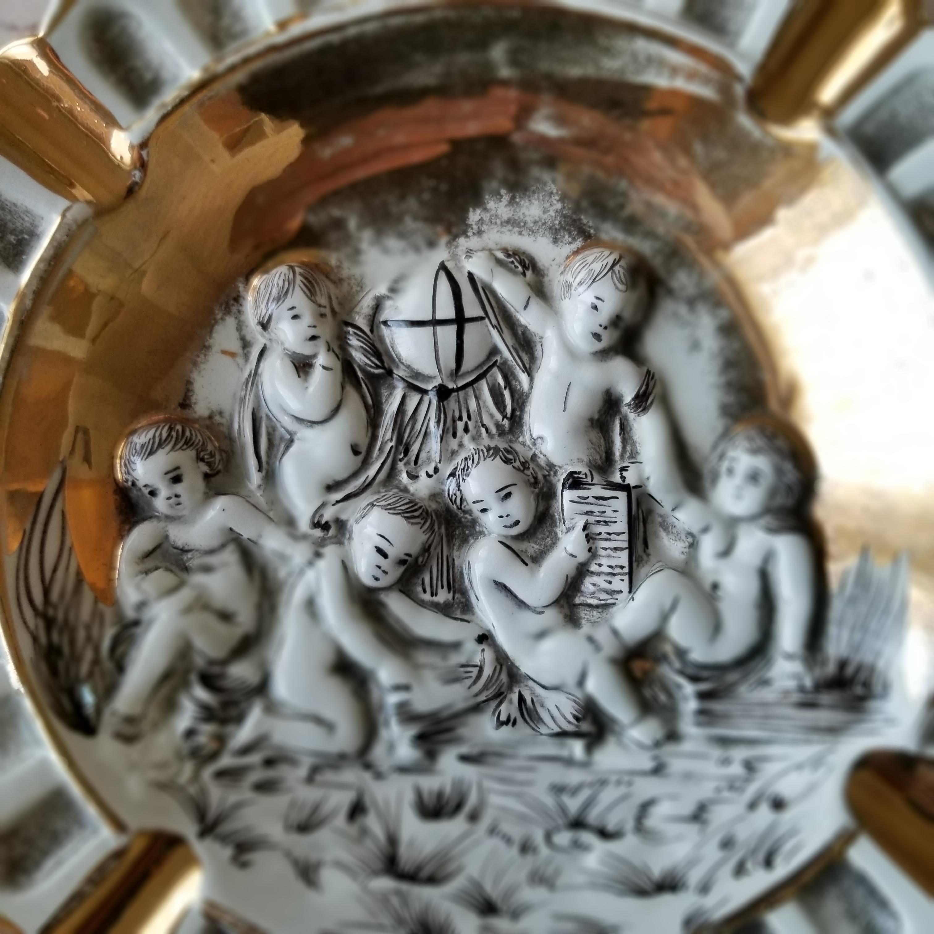 1960s Midcentury Modern Hollywood Regency Italian Gold Renaissance Cherub Ashtray 3.
Trimmed in 24kt Gold by Capodimonte signed stamped Italy.
7.5 x 7.5
Colors are Gold, Black and White.
Very good vintage condition. Lovely presentation.

