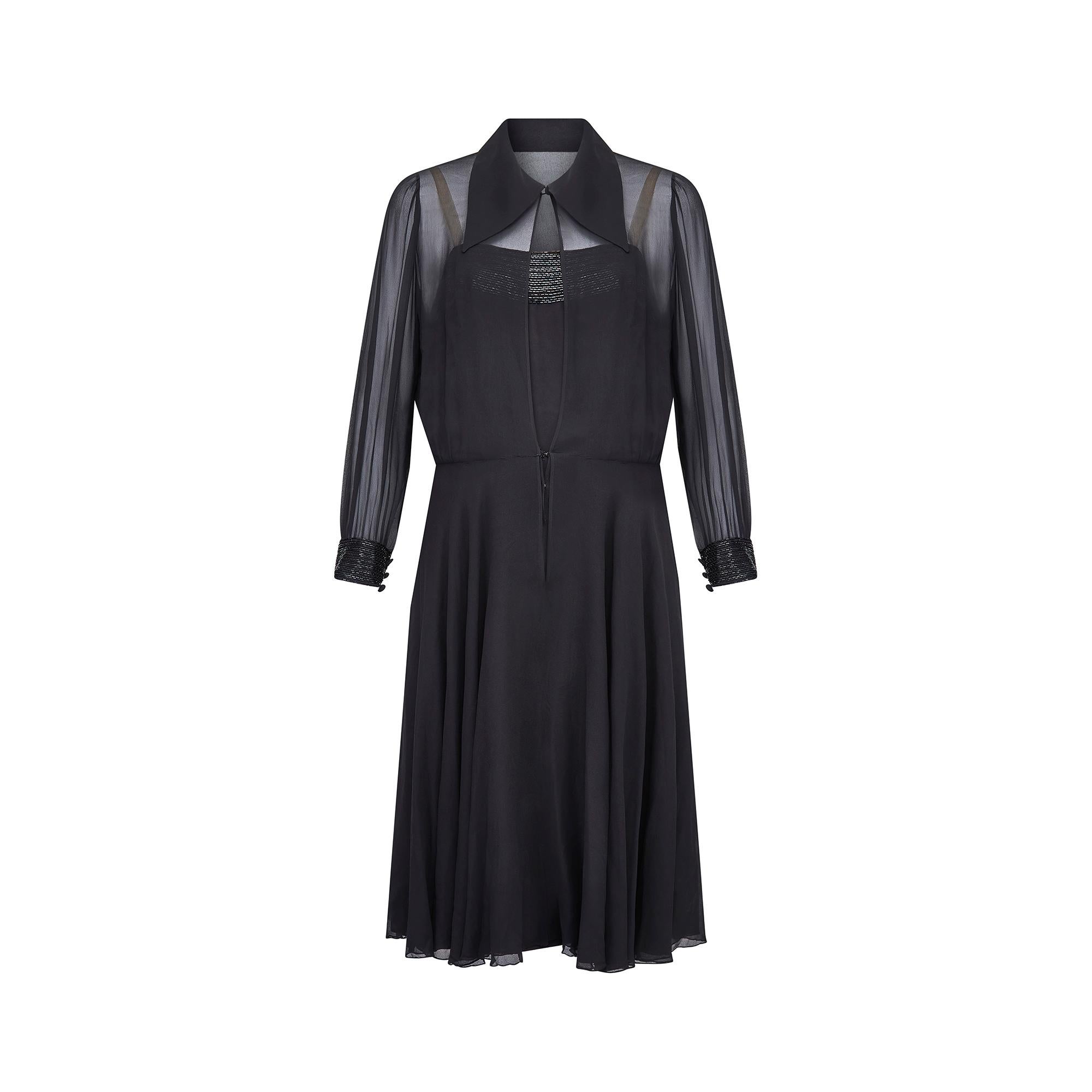 Designed by Jacqueline Godard in the late 1960s or early 1970s this elegant ensemble is formed of a slip dress and sheer, shirt-dress style top layer. Crafted from black finest silk chiffon, the pretty shirt layer has beaded cuffs, a double-layered
